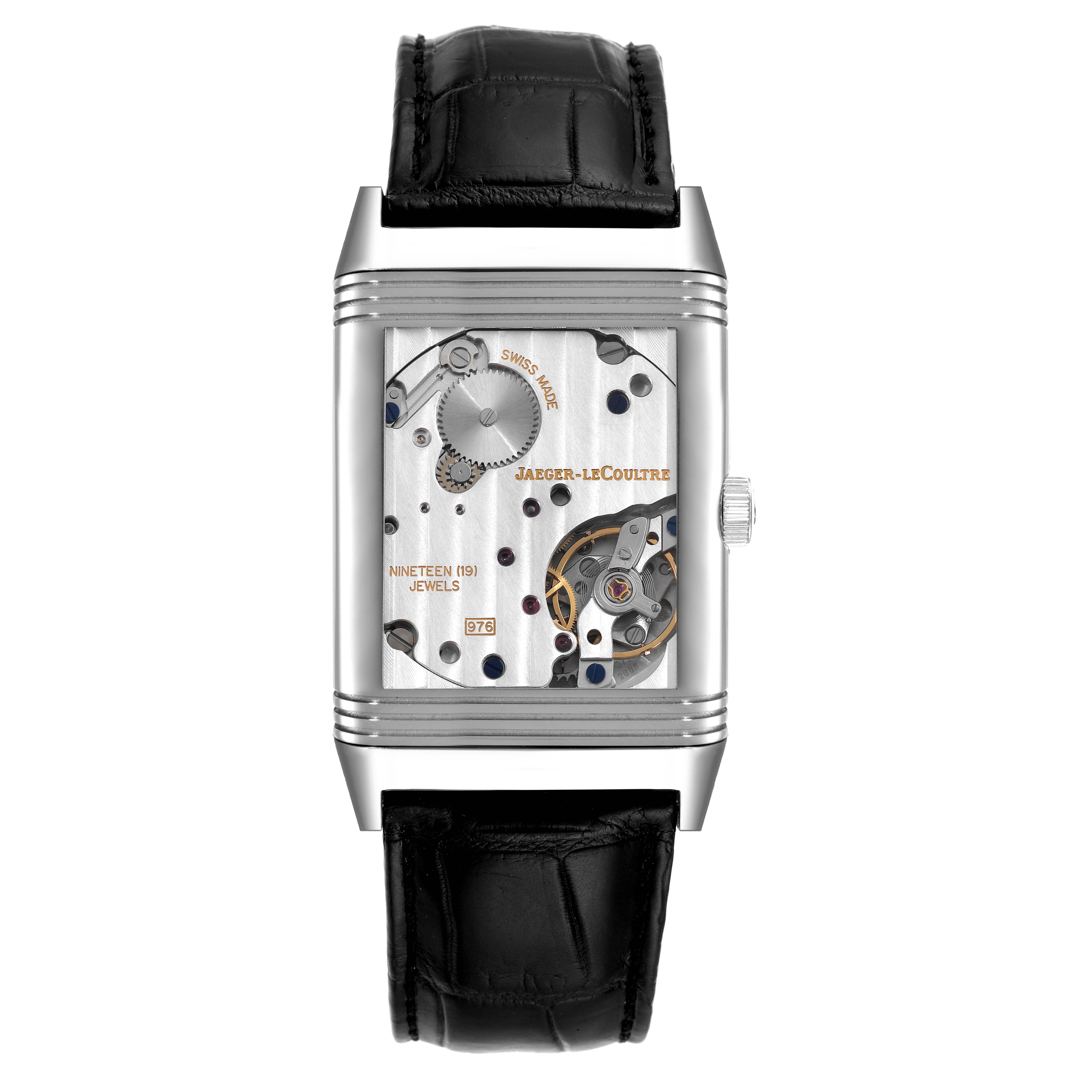 The image shows the back view of a Jaeger-LeCoultre Reverso watch, showcasing its exposed mechanical movement and inner components.