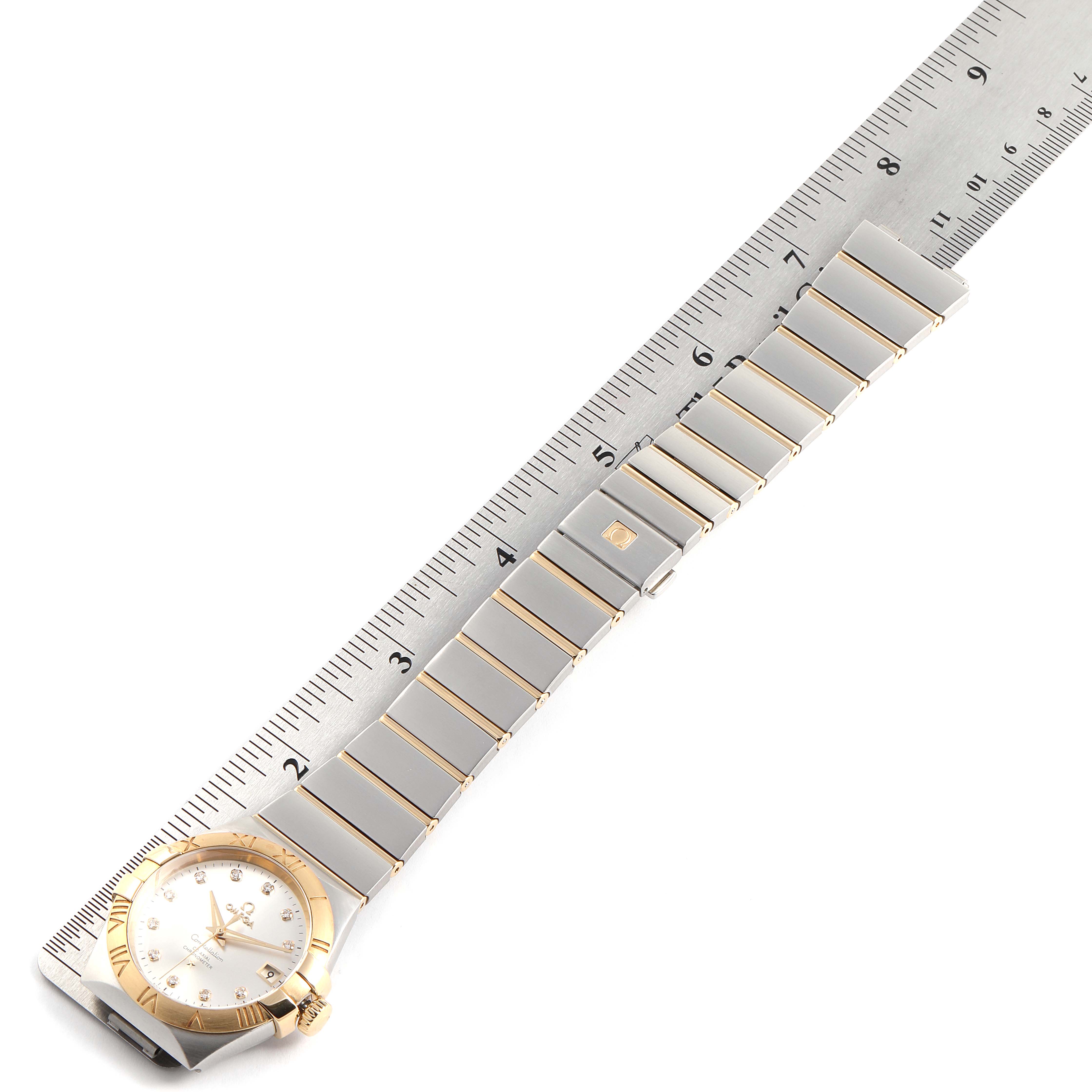 The image shows an Omega Constellation 111.20.36.20.52.001 Men
s Steel and Gold (two tone) Silver Dial 111.20.36.20.52.001 Men
s Steel and Gold (two tone) Silver Dial watch with its bracelet and dial positioned next to a ruler for size reference.