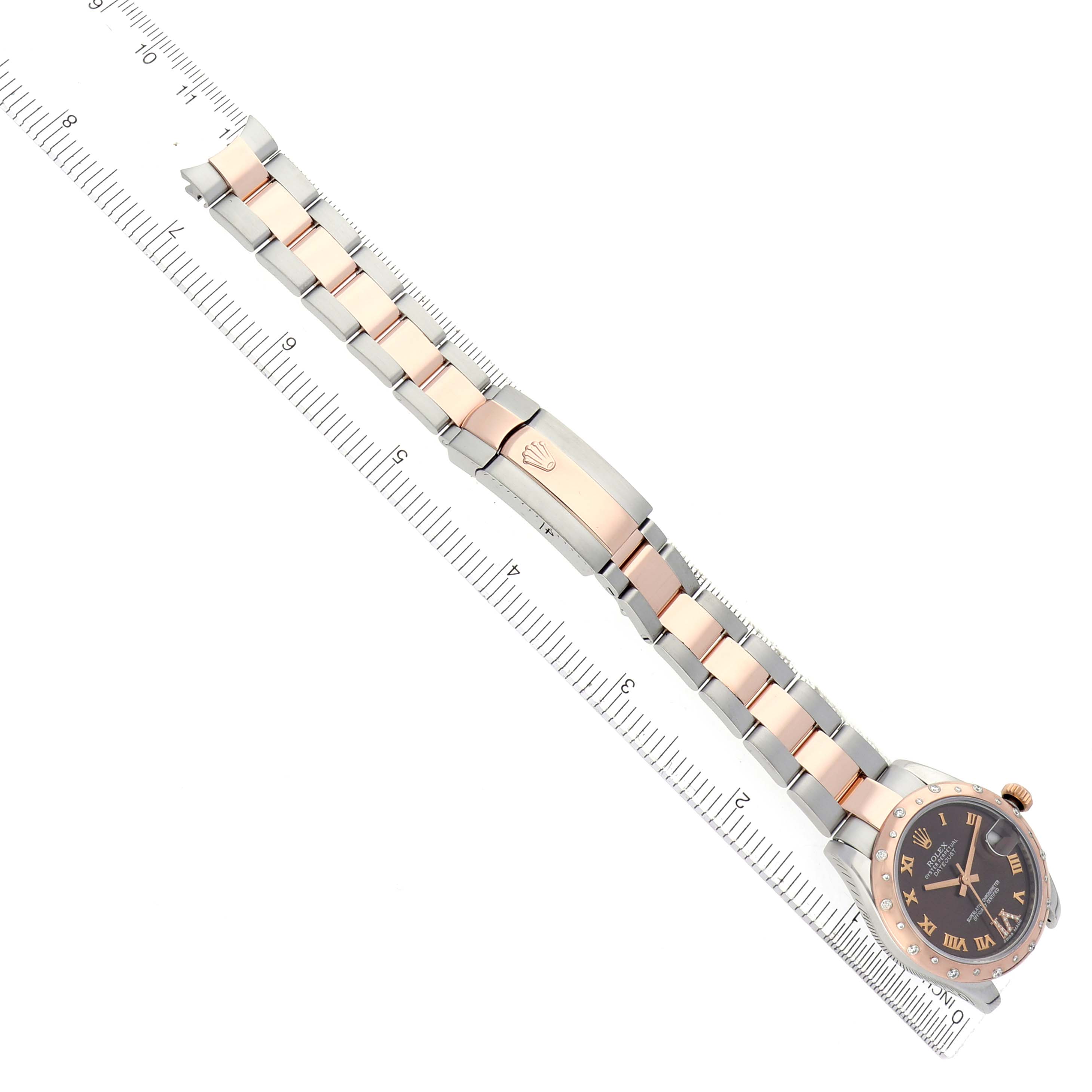 The Rolex Mid-Size 178341 Women
s Steel and Gold (two tone) Brown Dial watch is shown from a top-down angle, featuring the face, bracelet, and clasp on a ruler.