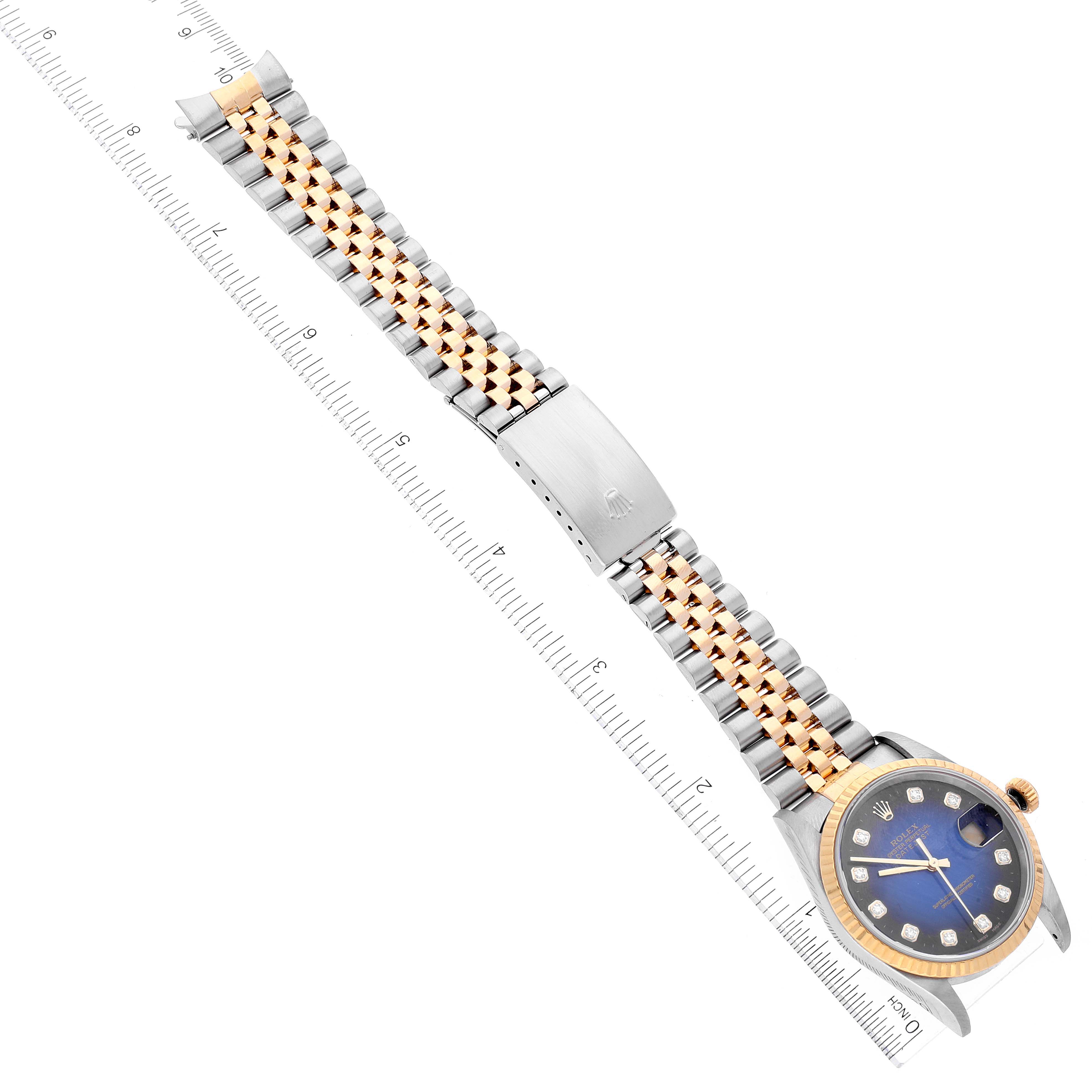 The image shows the Rolex Datejust 16233 Men's Steel and Gold (two tone) Blue Dial 16233 Men's Steel and Gold (two tone) Blue Dial watch laid flat, showcasing the face, bezel, and two-tone bracelet with a ruler for scale.