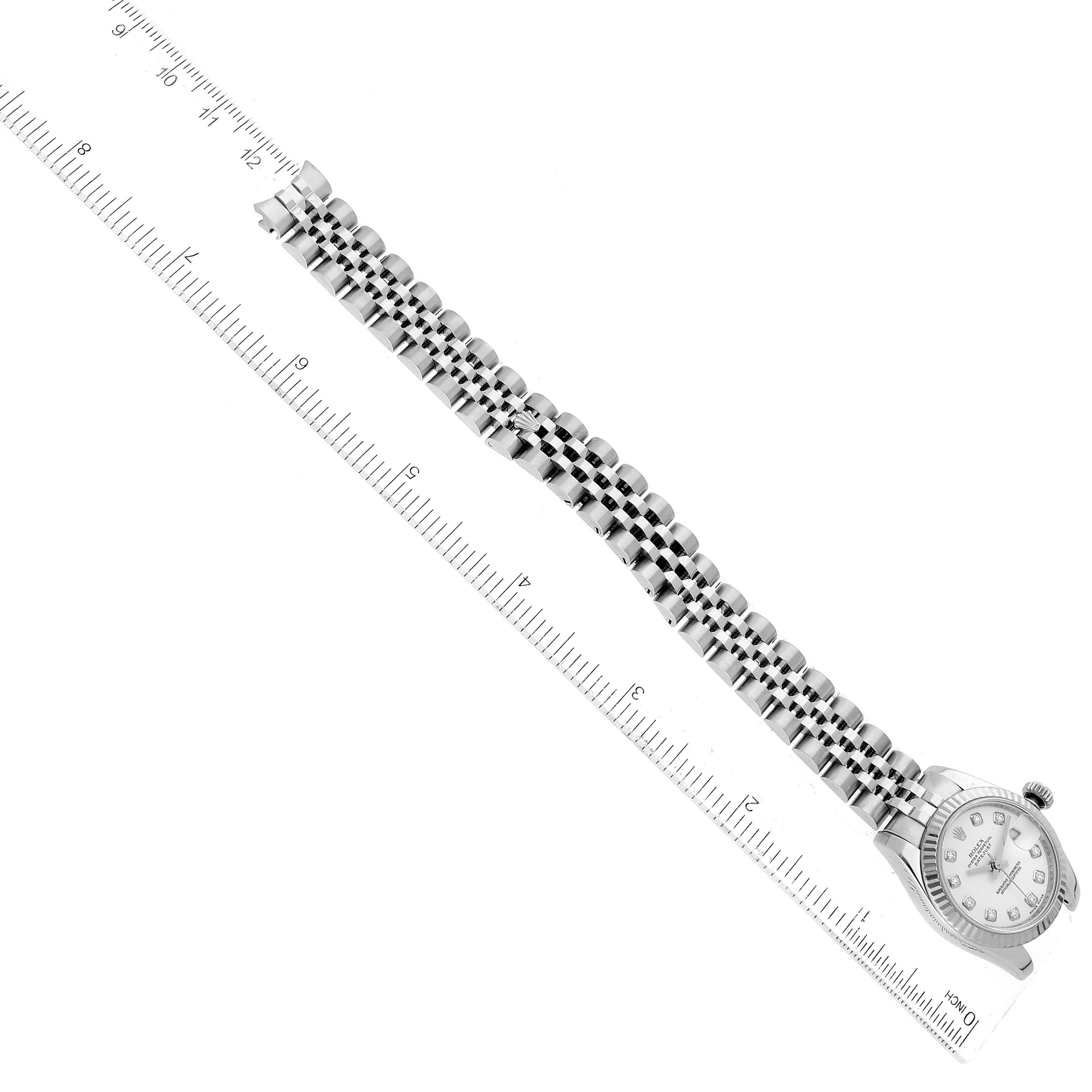 The image shows a close-up, top-down view of a Rolex Datejust 179174 Women
s Stainless Steel White Dial 179174 Women
s Stainless Steel White Dial watch and its bracelet next to a ruler for scale.