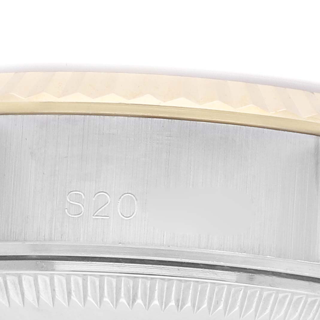 The image shows a close-up of the side and bezel of a Rolex Datejust 69173 Women
s Steel and Gold (two tone) Champagne Dial, highlighting the fluted edge and part of the case side engraving.