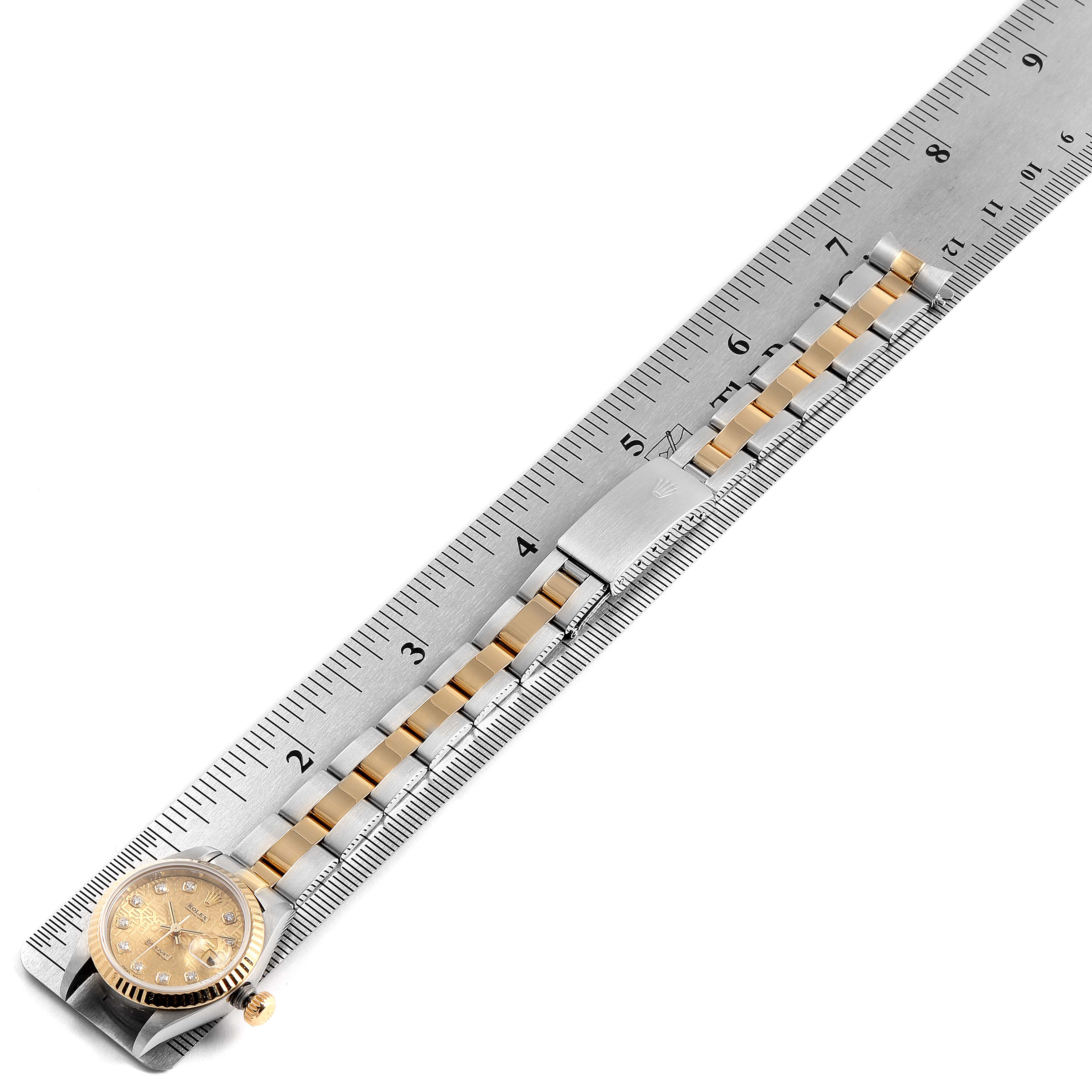 The image shows a Rolex Datejust 79173 Women's Steel and Gold (two tone) Champagne Dial 79173 Women's Steel and Gold (two tone) Champagne Dial watch placed next to a ruler, highlighting its face, crown, and bracelet.