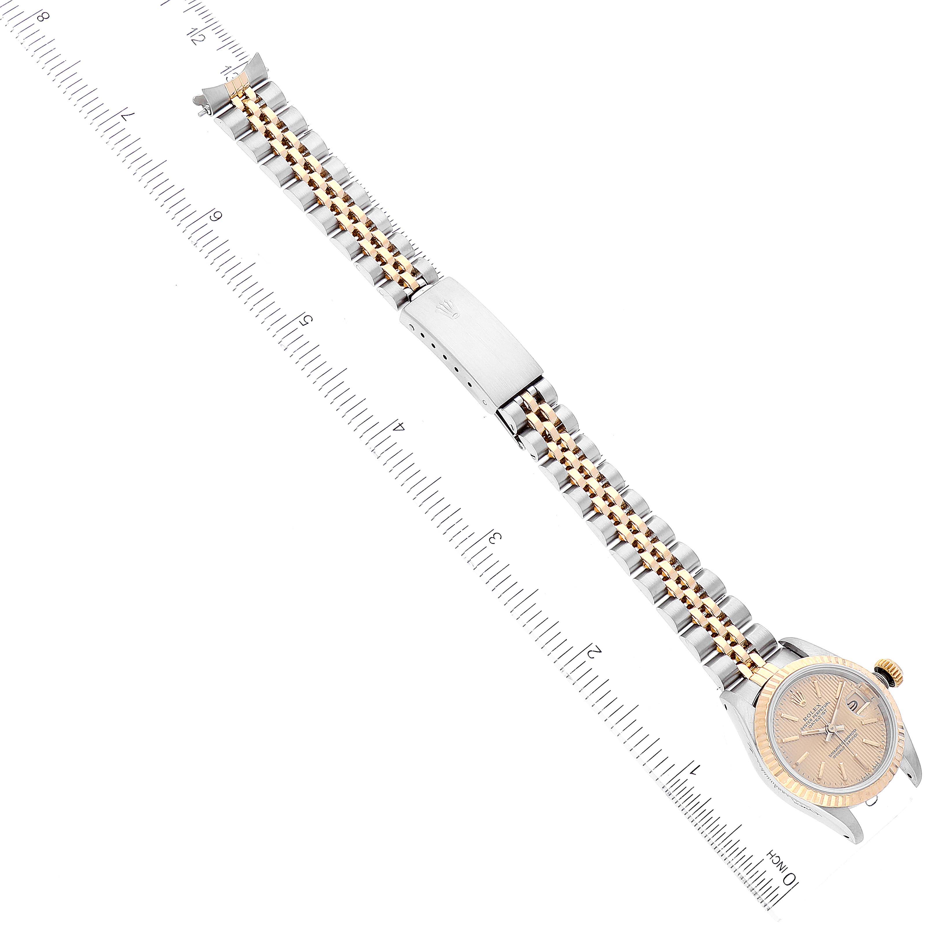 The image shows the Rolex Datejust 69173 Women's Steel and Gold (two tone) Champagne Dial 69173 Women's Steel and Gold (two tone) Champagne Dial watch laying flat with its face, bracelet, and clasp visible, alongside a measuring scale.