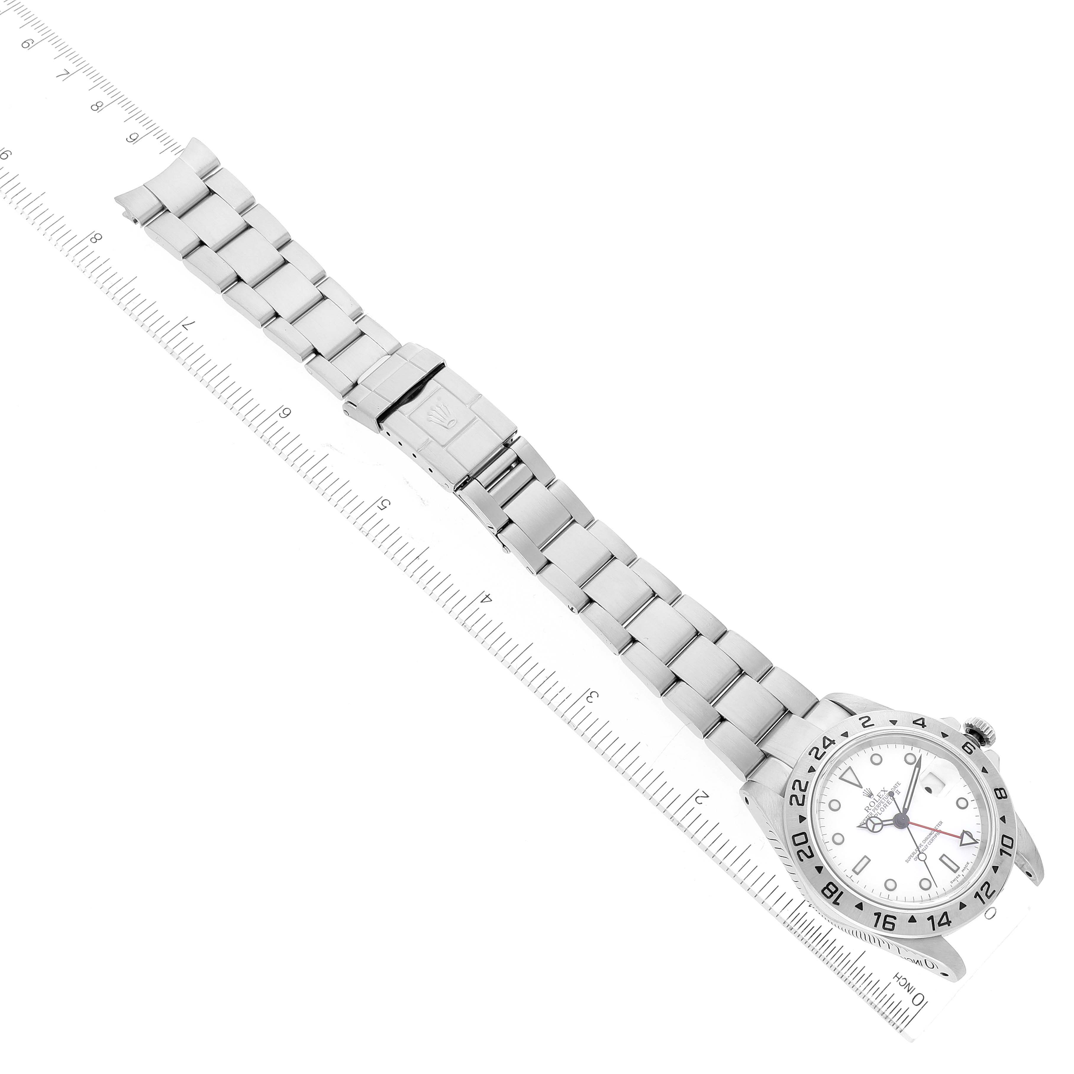 The Rolex Explorer 16570 Men's Stainless Steel White Dial 16570 Men's Stainless Steel White Dial watch is displayed flat, showcasing its face, bezel, and metal bracelet alongside a ruler for scale.