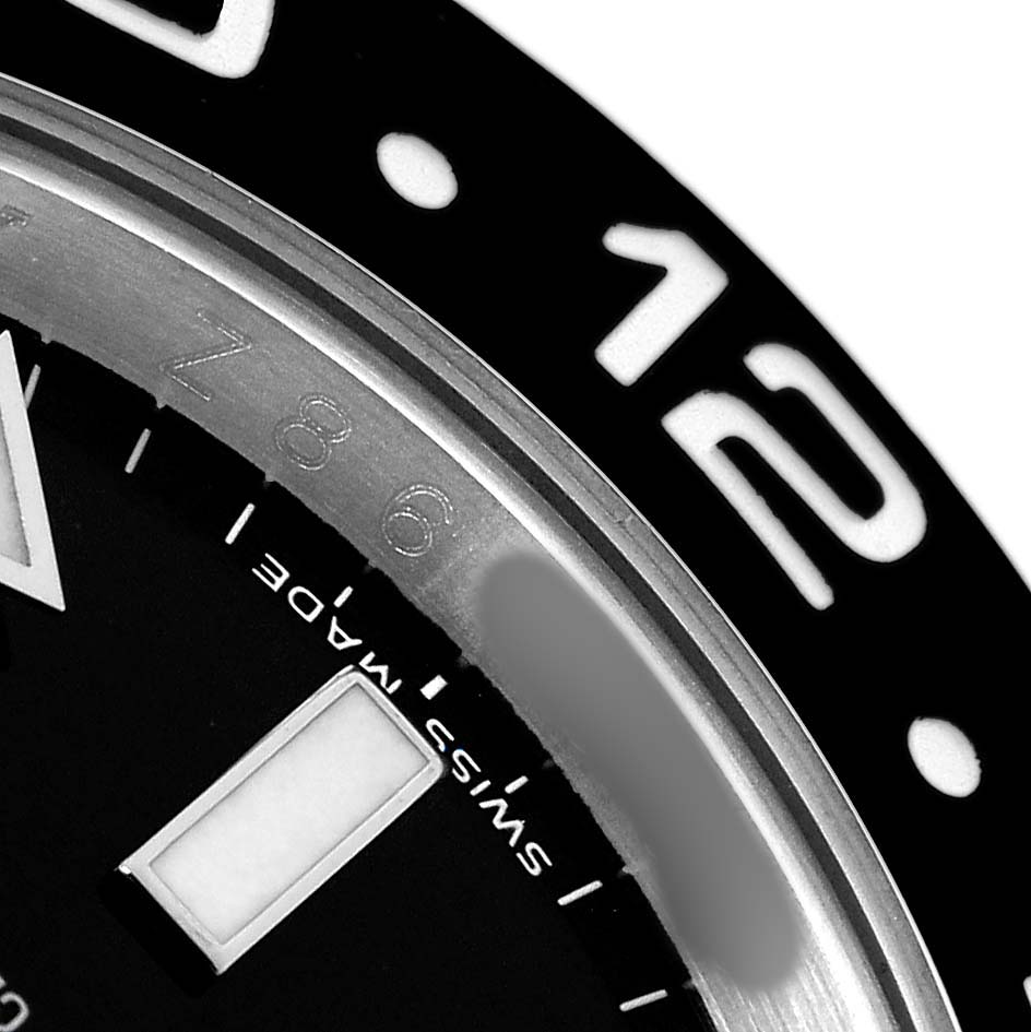 The image shows a close-up of the bezel and dial edge of a Rolex GMT-Master 116710 Men
s Stainless Steel Black Dial, highlighting the "12" hour marker and "Swiss Made" text.