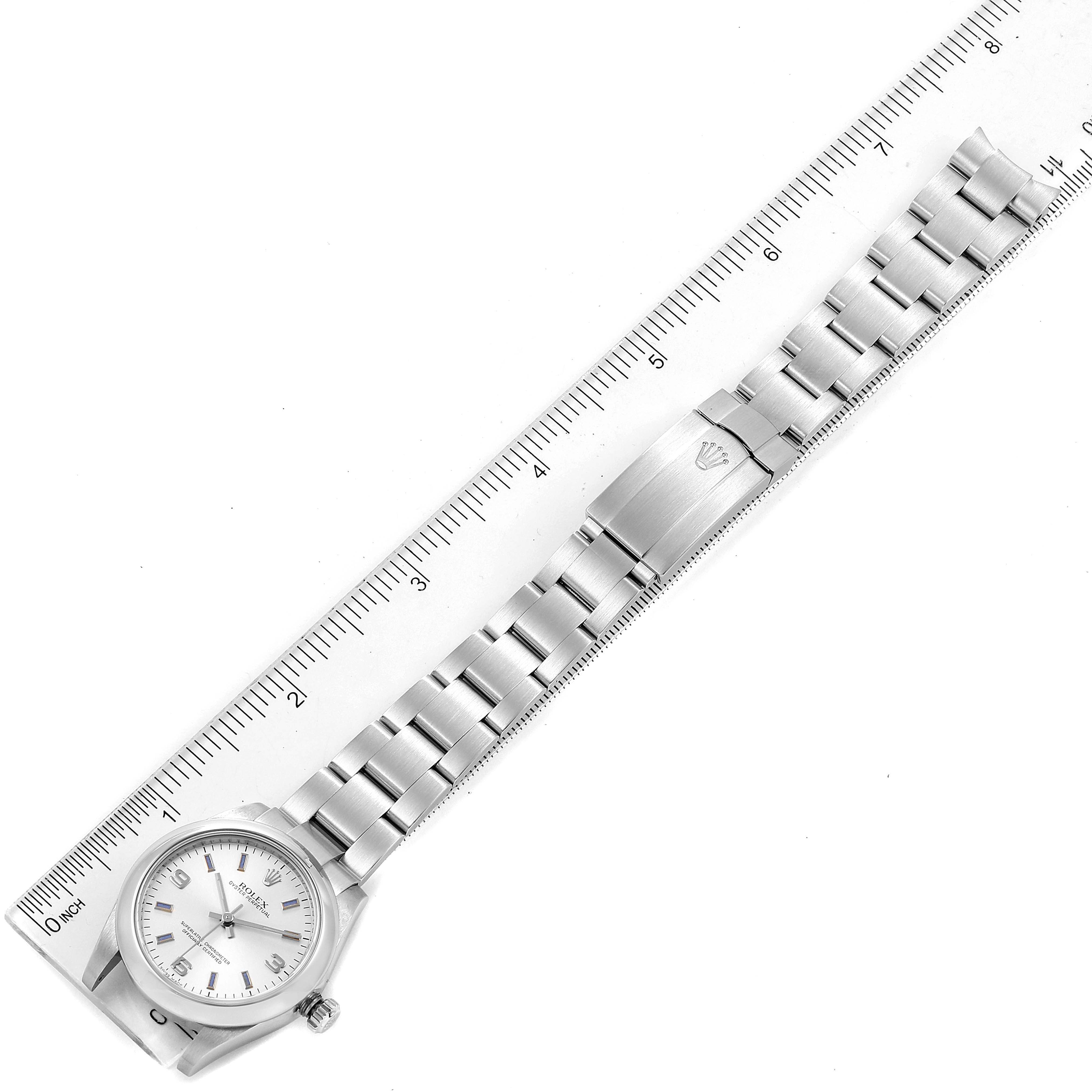 The image shows a top view of a Rolex Mid-Size 177200 Women
s Stainless Steel Silver Dial 177200 Women
s Stainless Steel Silver Dial watch, including the case, dial, crown, bracelet, and clasp, beside a ruler.