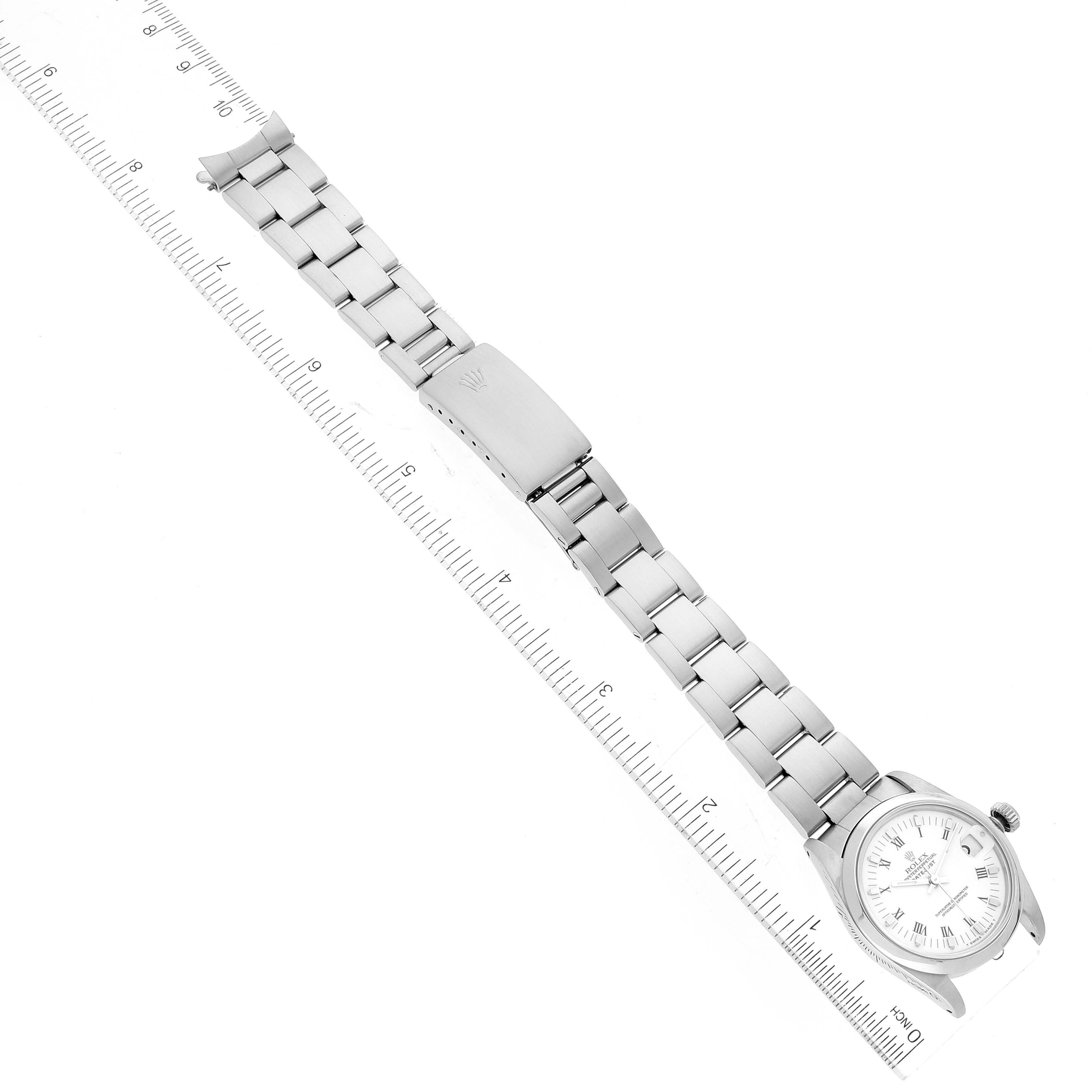 The Rolex Mid-Size 68240 Women's Stainless Steel White Dial 68240 Women's Stainless Steel White Dial watch is shown from an overhead angle, displaying its stainless steel bracelet, clasp, and dial beside a ruler.