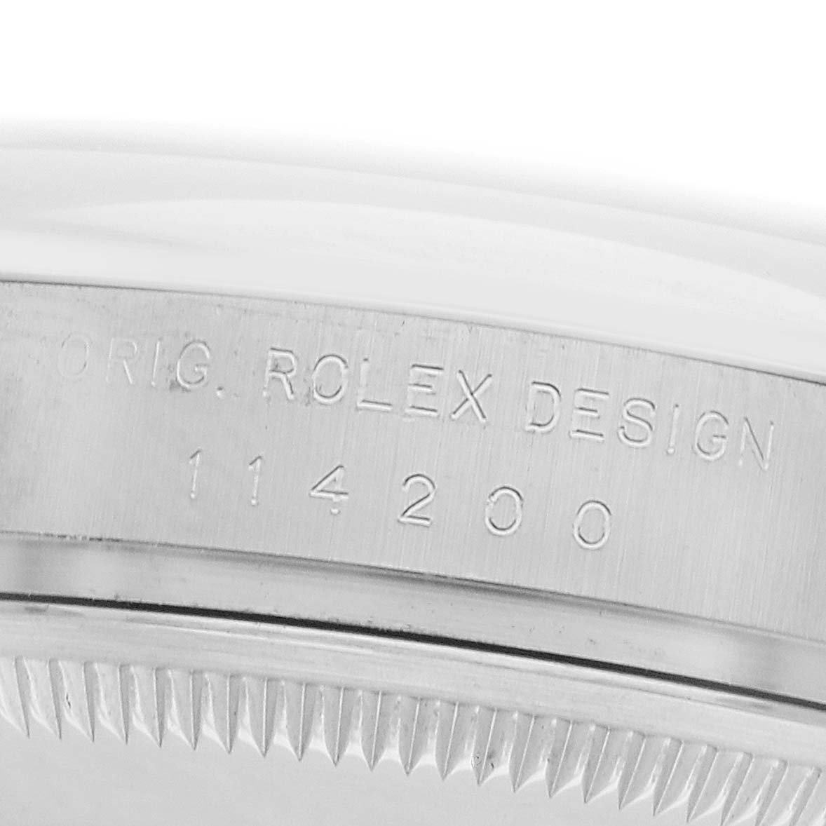 The image shows the side view of a Rolex Oyster Perpetual 114200 Men's Stainless Steel White Dial, highlighting the engraved serial and model numbers on its case.