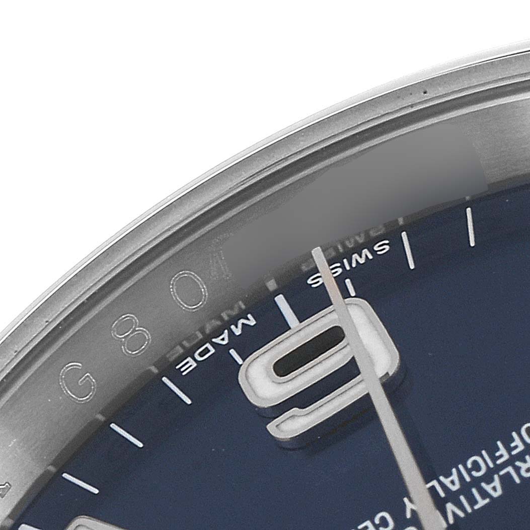 This image shows a close-up angle of the dial and part of the bezel of a Rolex Oyster Perpetual 116000 Men
s Stainless Steel Blue Dial 116000 Men
s Stainless Steel Blue Dial watch, including the "9" marker and "Swiss Made" text.
