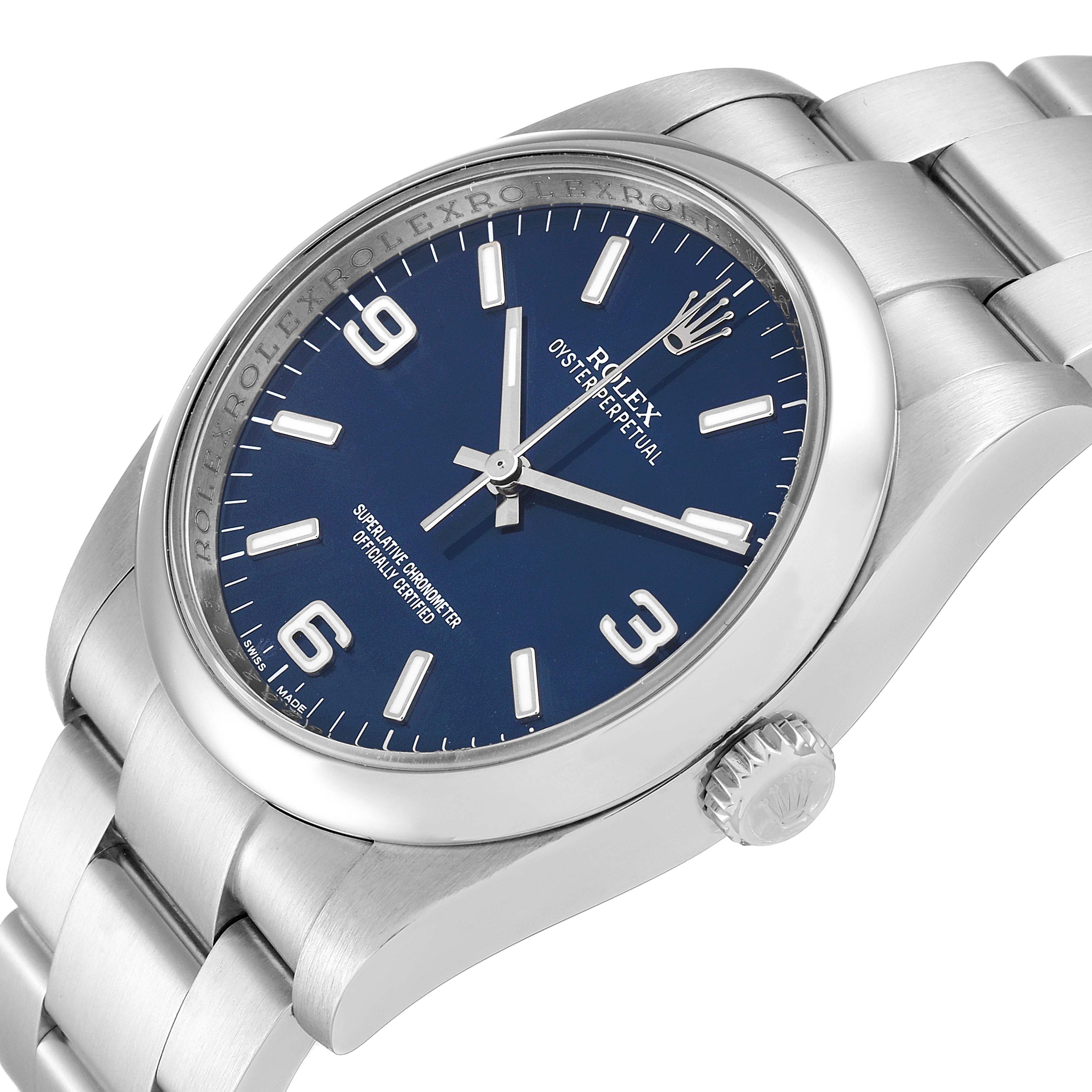 The image shows a side-angle view of the Rolex Oyster Perpetual 116000 Men
s Stainless Steel Blue Dial 116000 Men
s Stainless Steel Blue Dial watch, highlighting the blue dial, case, crown, and stainless steel bracelet.