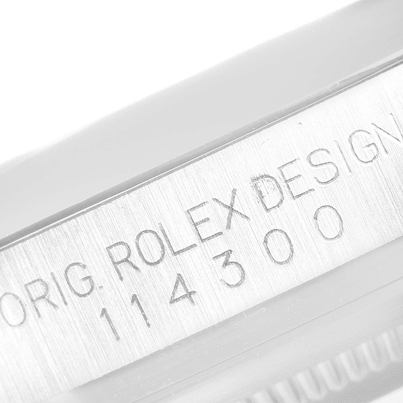 The image shows a close-up of the case side engraving on a Rolex Oyster Perpetual 114300 Men's Stainless Steel Black Dial 114300 Men's Stainless Steel Black Dial watch, displaying the model number 114300.