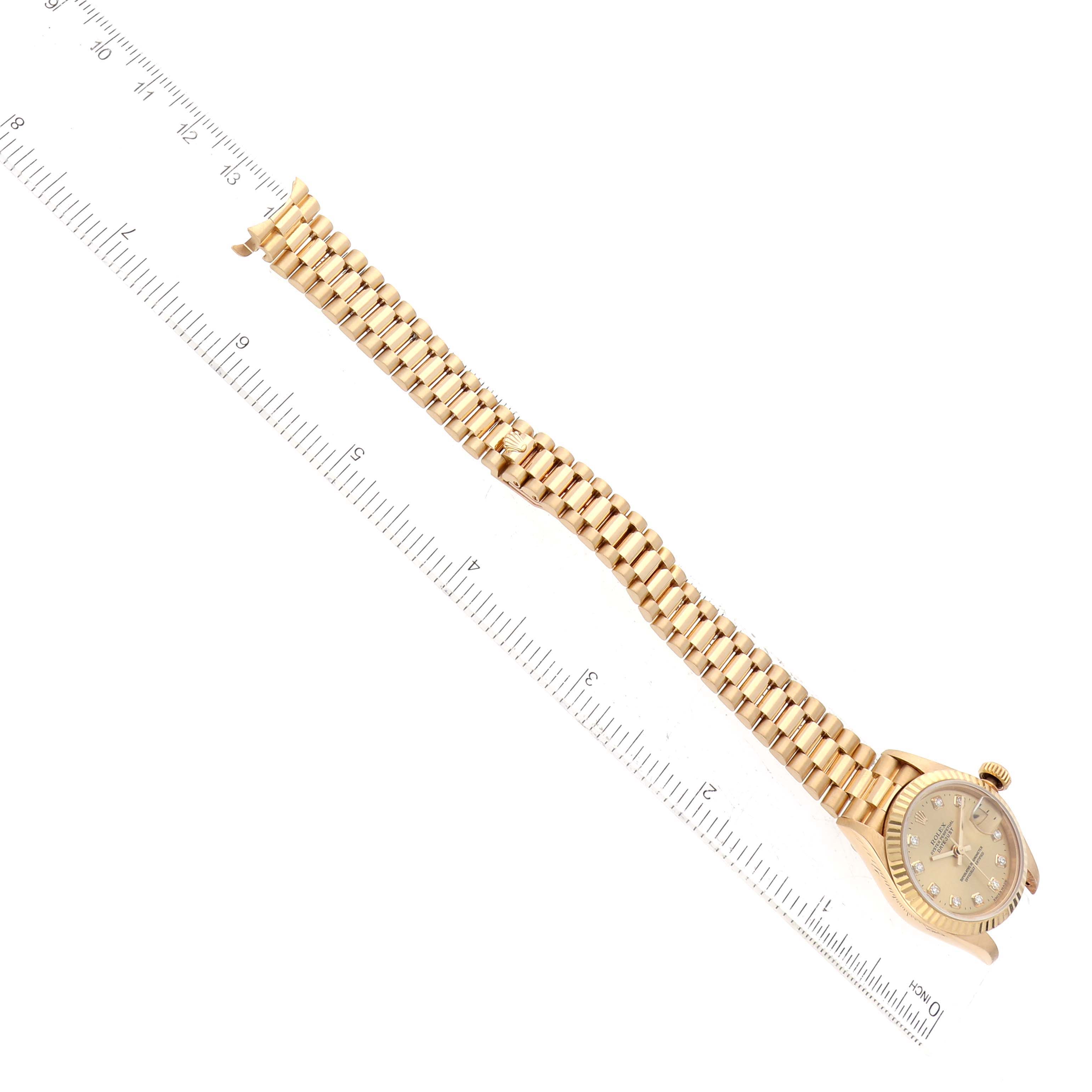 The image shows a Rolex President 79178 Women's Yellow Gold Champagne Dial 79178 Women's Yellow Gold Champagne Dial model watch laid flat next to a ruler, highlighting the watch face and full bracelet.