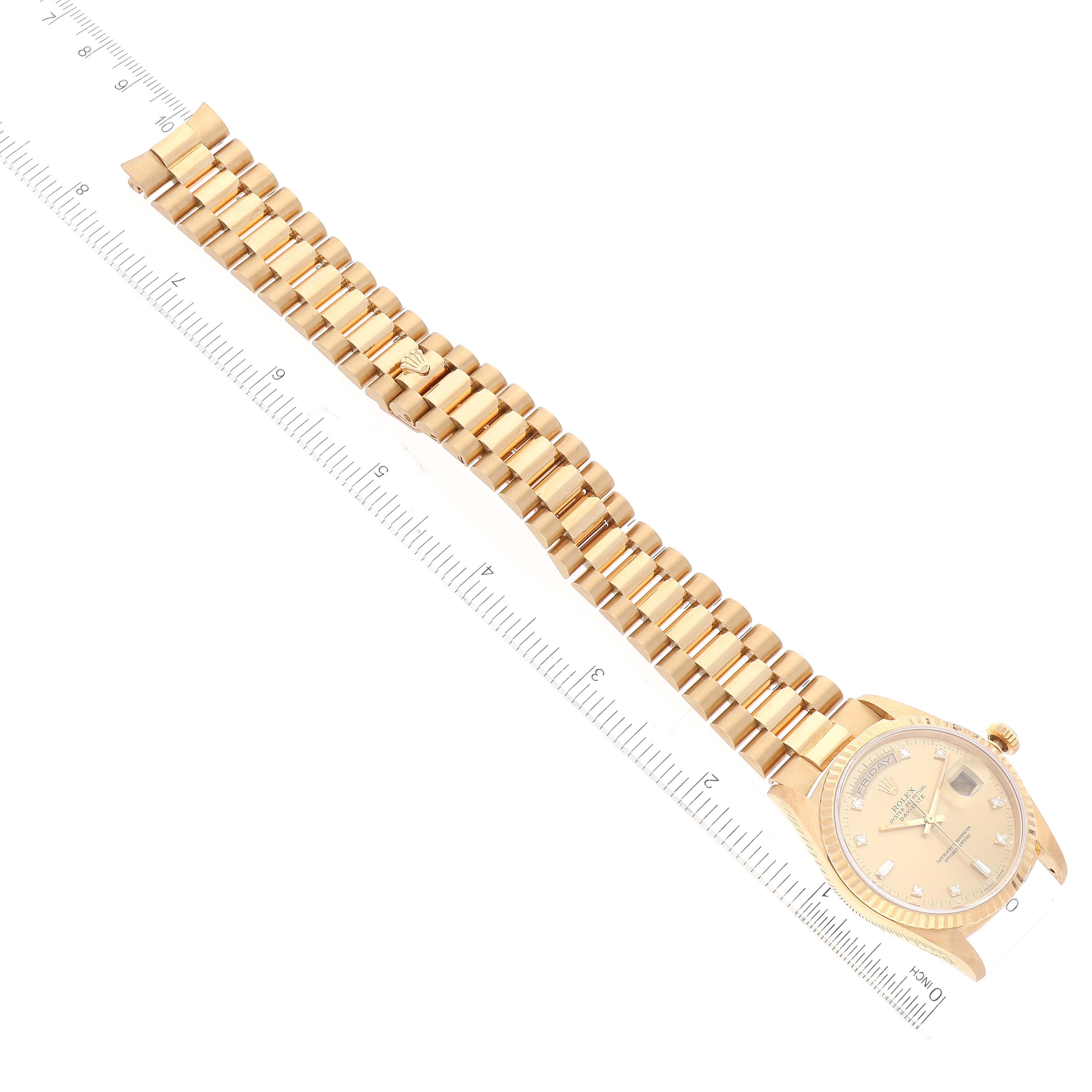 The image shows an overhead view of a Rolex President 18238 Men
s Yellow Gold Champagne Dial 18238 Men
s Yellow Gold Champagne Dial model watch with a gold bracelet and beige dial, next to a ruler.