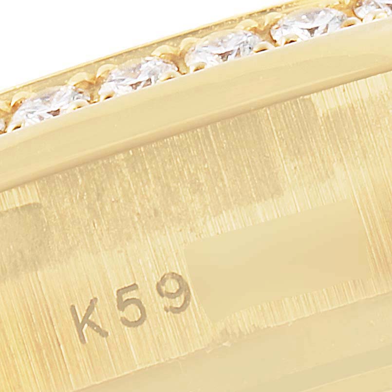 This is a close-up of a gold Rolex President 179138 Women
s Yellow Gold Mother of Pearl Dial 179138 Women
s Yellow Gold Mother of Pearl Dial watch, showing part of the bezel set with diamonds and a serial number engraving.