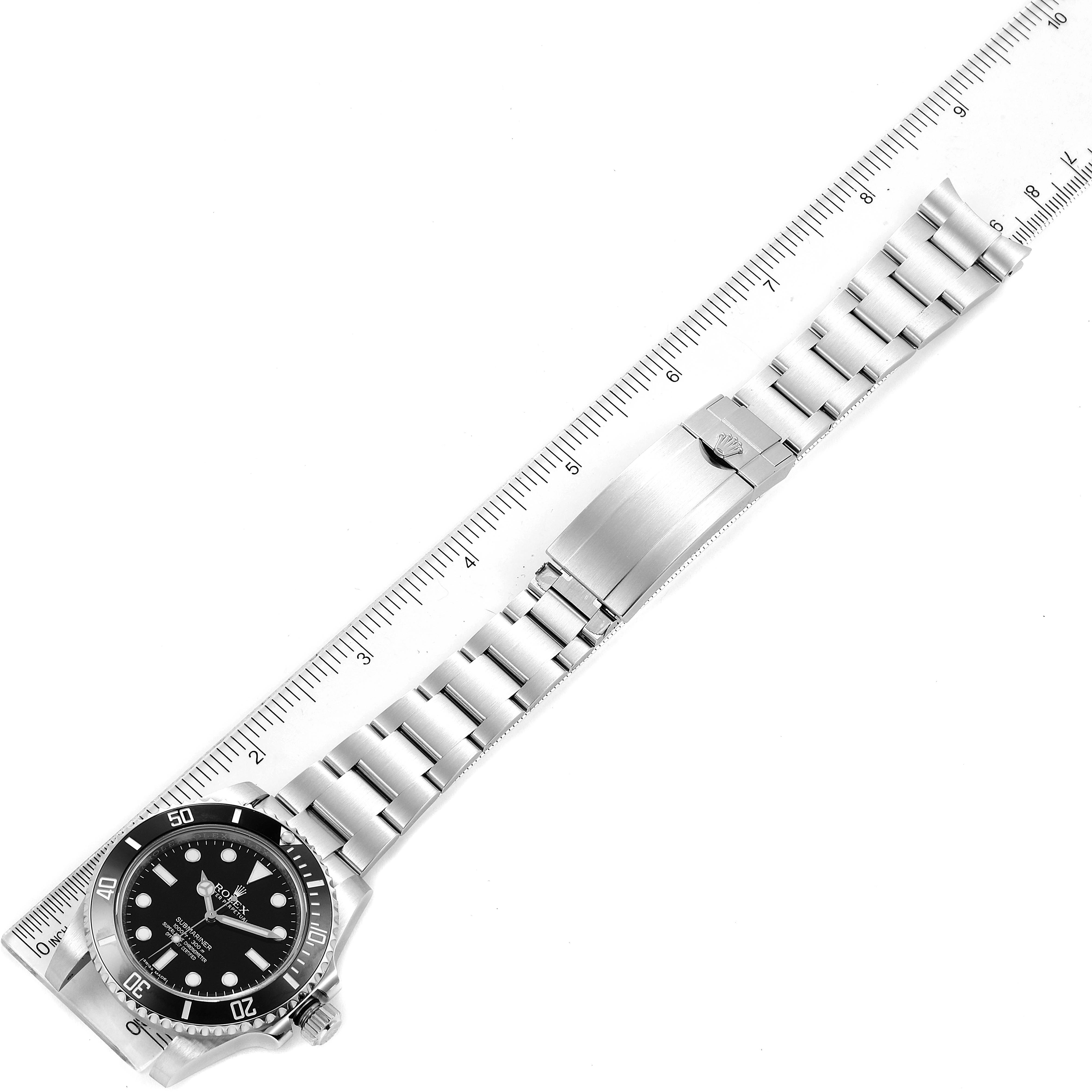 The image shows a top-down view of a Rolex Submariner 114060 Men
s Stainless Steel Black Dial 114060 Men
s Stainless Steel Black Dial watch, displaying the watch face, bezel, and metal bracelet against a ruler for measurement.