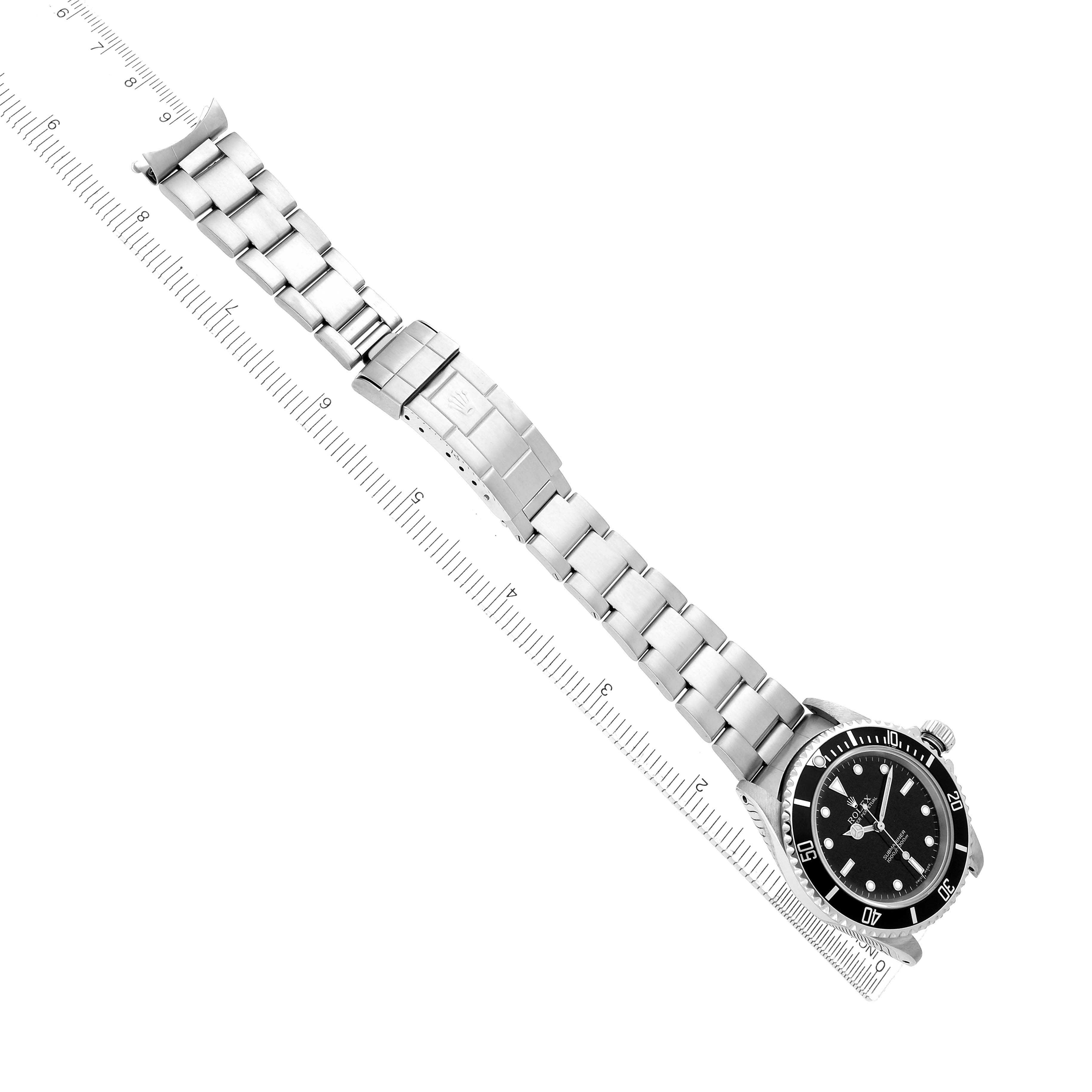 The image shows a Rolex Submariner 14060M Men
s Stainless Steel Black Dial watch at an oblique angle, highlighting its bracelet, clasp, and dial against a measuring ruler.