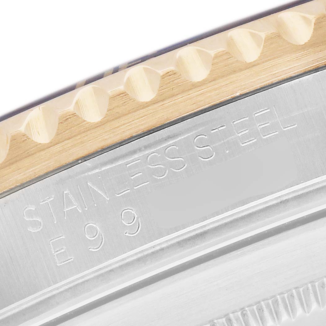 The image shows a close-up of a Rolex Submariner 16613 Men
s Steel and Gold (two tone) Champagne Dial
s stainless steel edge and bezel, highlighting the engraved details.