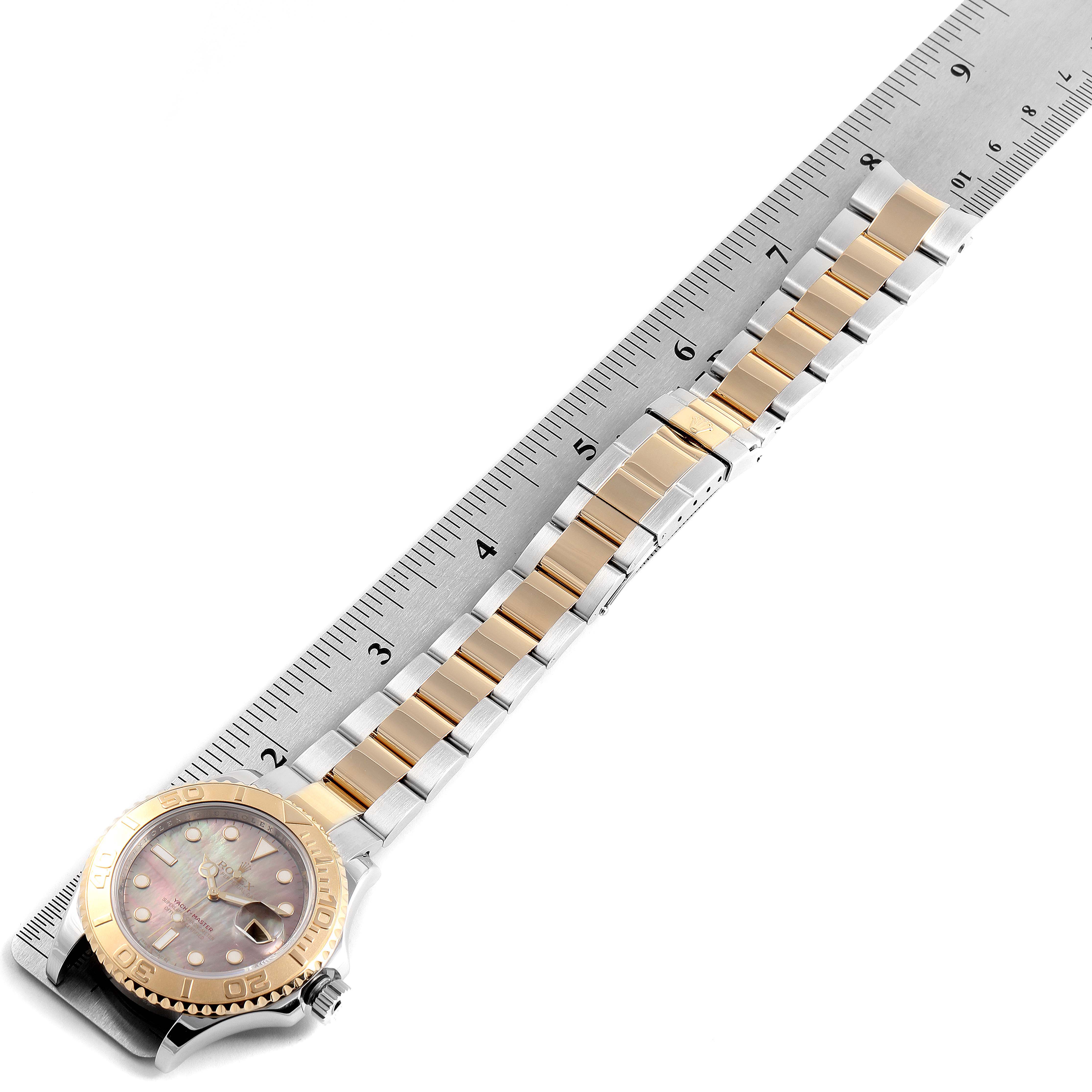 The image shows a top-down view of a Rolex Yacht-Master 16623 Men's Steel and Gold (two tone) Mother of Pearl Dial 16623 Men's Steel and Gold (two tone) Mother of Pearl Dial watch with a close-up of its bracelet and face, placed next to a ruler.
