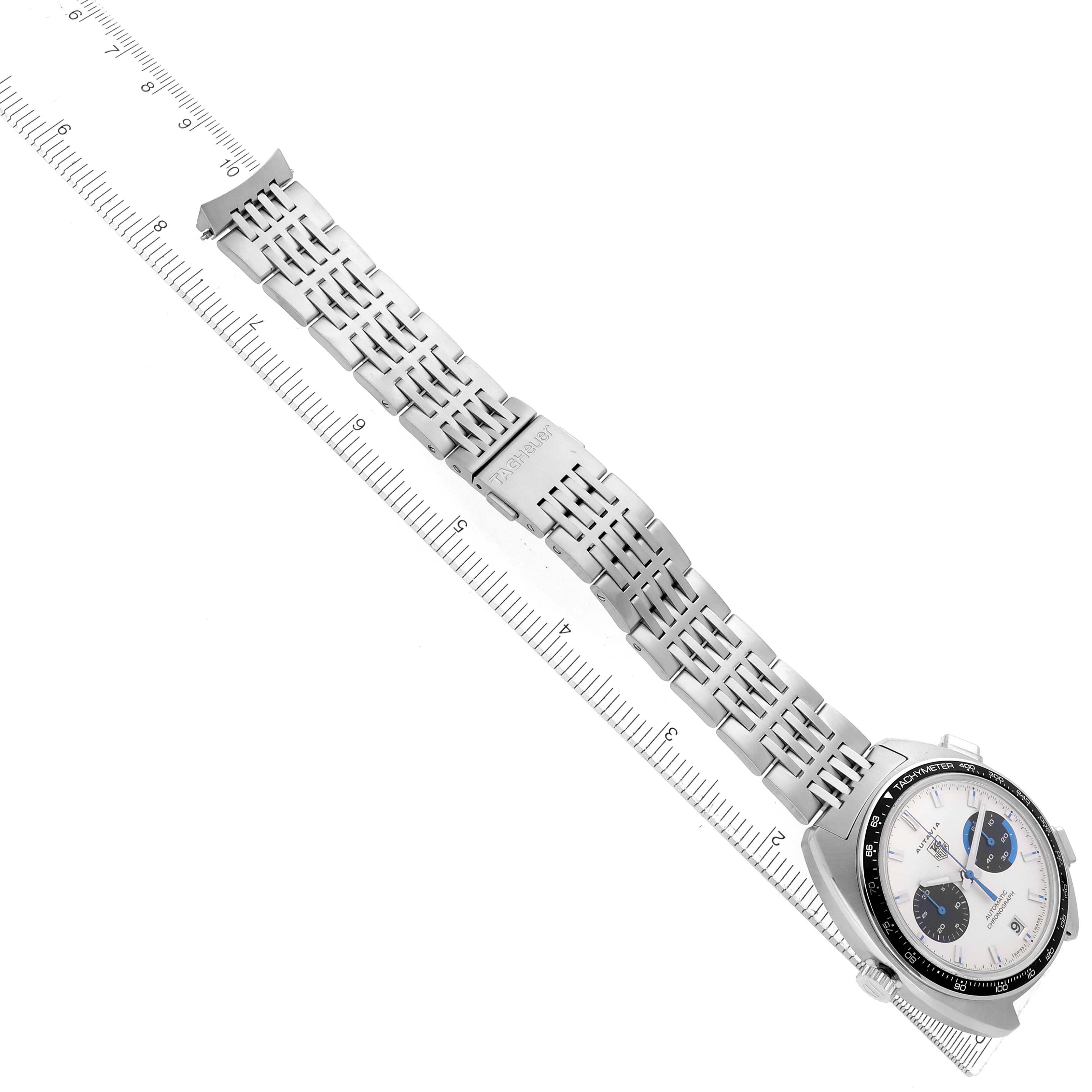 The Tag Heuer Autavia CY2110 Men
s Stainless Steel White Dial watch is shown at an angle displaying its dial, bezel, and full metal bracelet laid alongside a ruler.