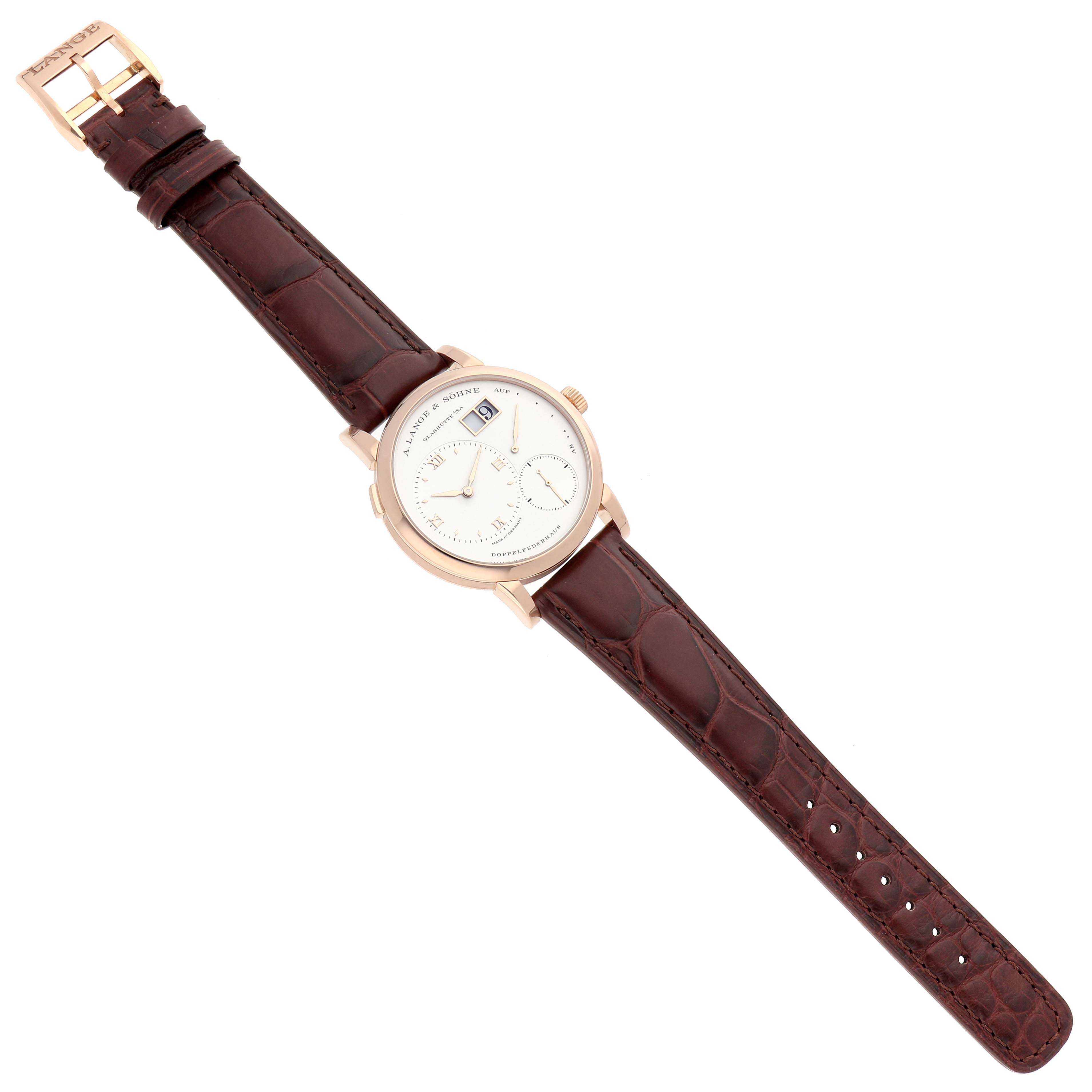 The A. Lange 
Sohne Lange 1 191.032 Men
s Rose Gold Silver Dial watch is shown from a top-down angle, featuring its face, strap, and buckle.