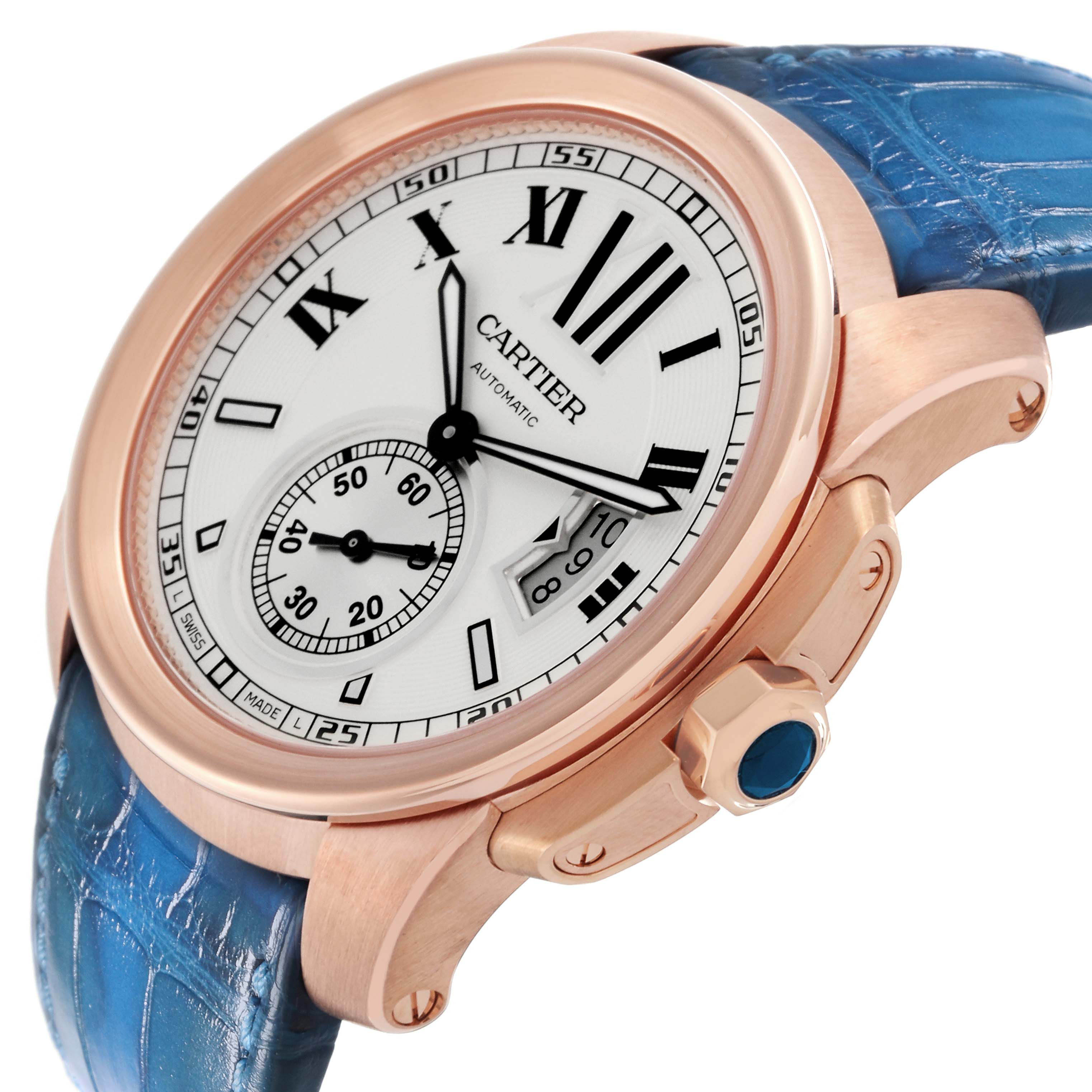 The image shows a close-up of the face and side of the Calibre de Cartier watch by Cartier, featuring its blue strap and rose gold casing.