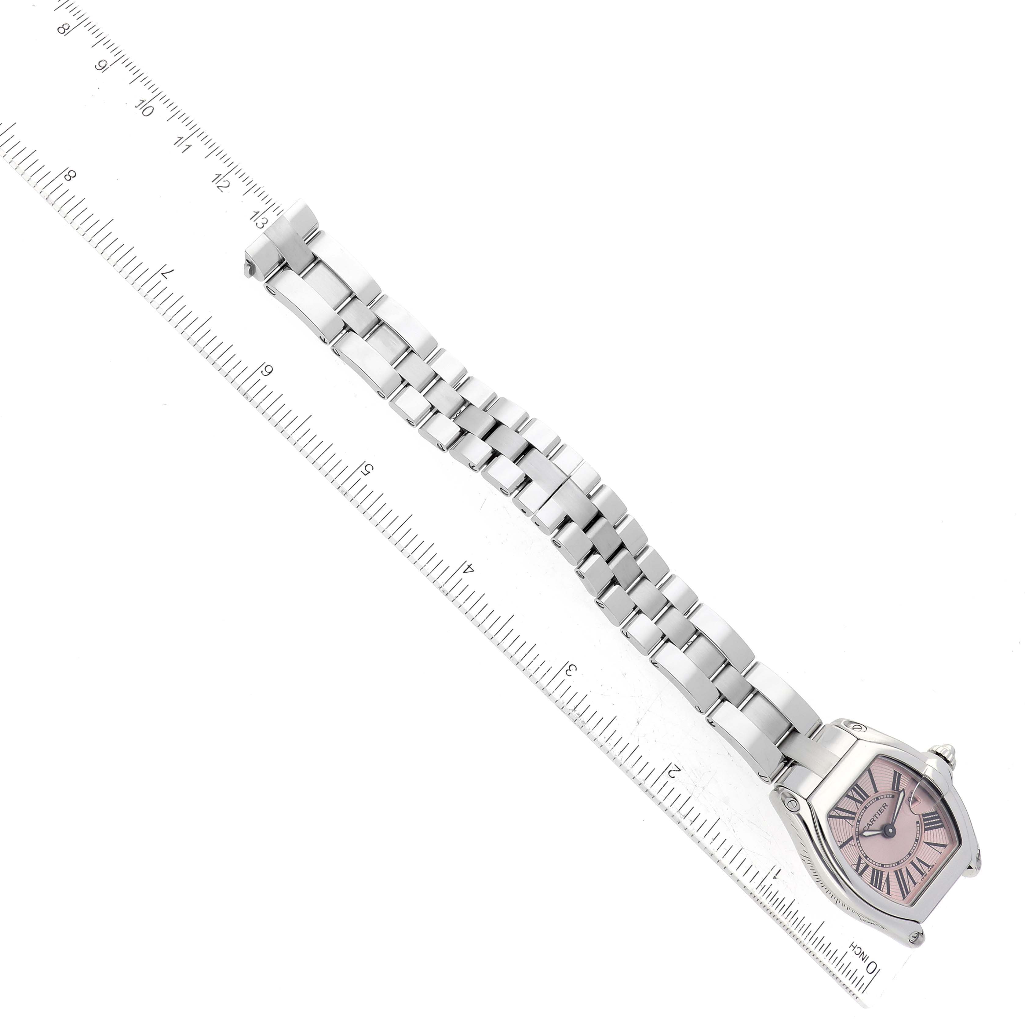 The Cartier Roadster W62017V3 Women's Stainless Steel Pink Dial W62017V3 Women's Stainless Steel Pink Dial watch is shown from a top-down angle, displaying the entire bracelet and face next to a ruler for scale.