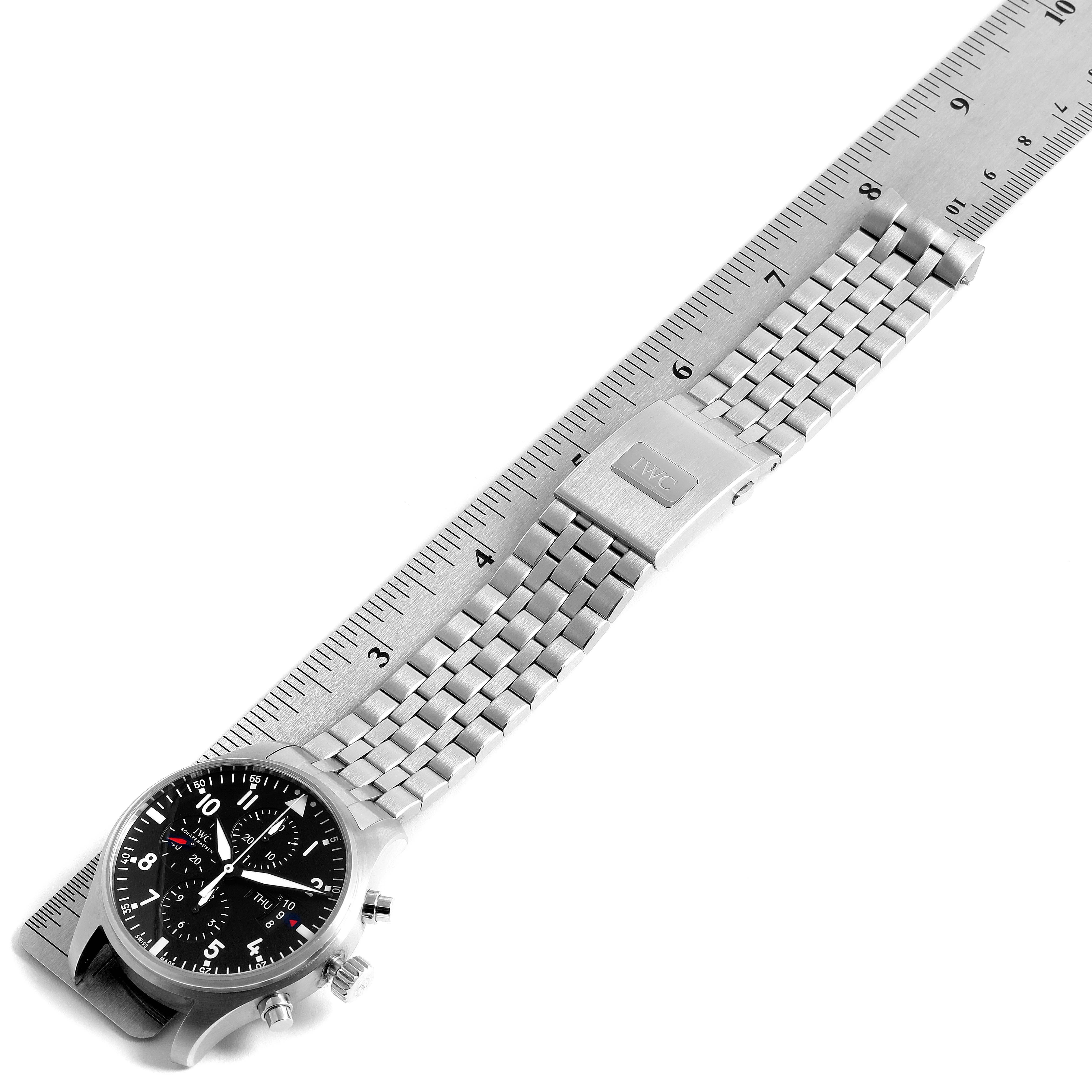 The IWC Pilot IW377704 Men's Stainless Steel Black Dial IW377704 Men's Stainless Steel Black Dial model watch is shown flat with its bracelet extended, next to a ruler for size reference.
