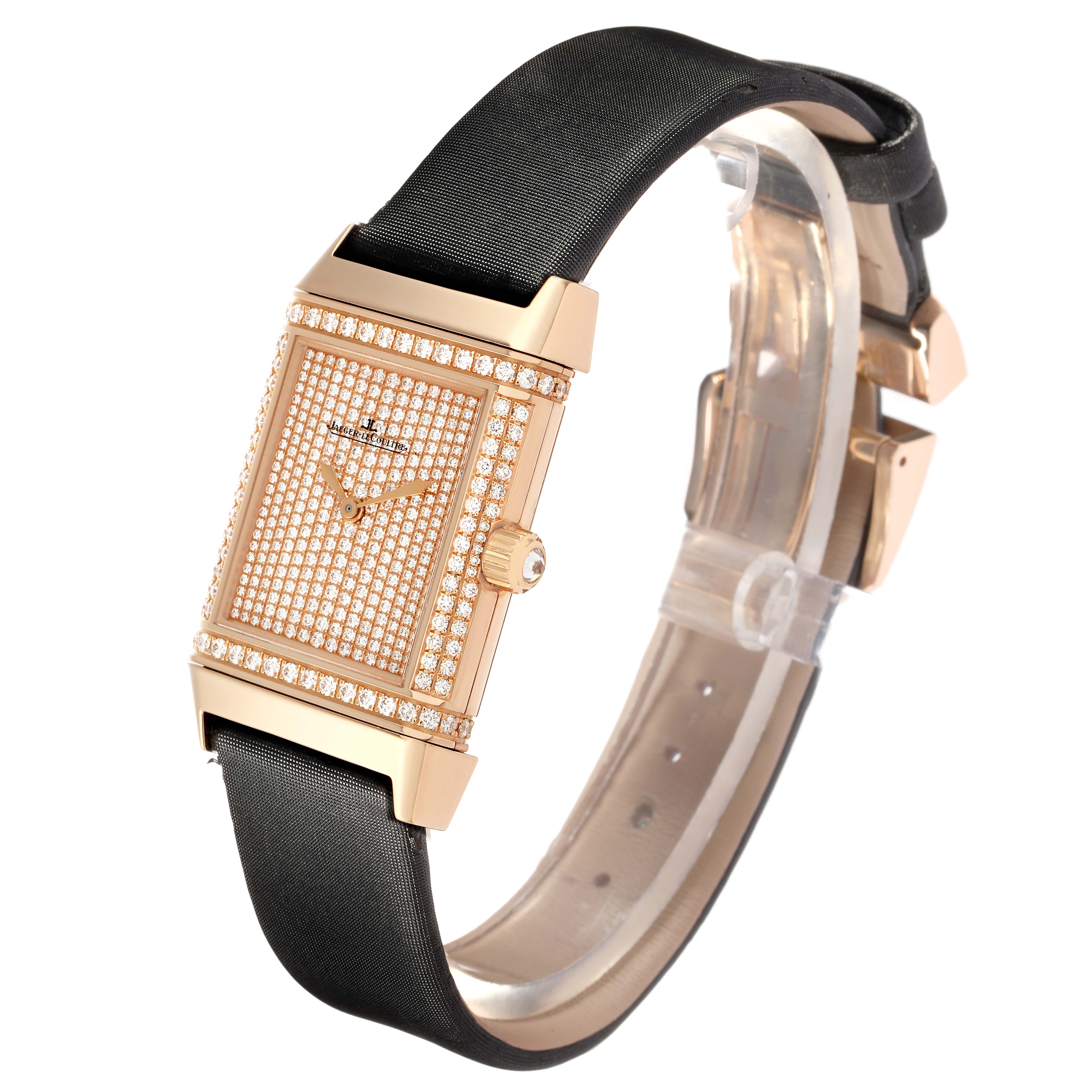 The Jaeger LeCoultre Reverso Q2562407 Women
s Rose Gold Pink Dial watch is shown at a slight angle, highlighting its diamond-encrusted face and black strap.