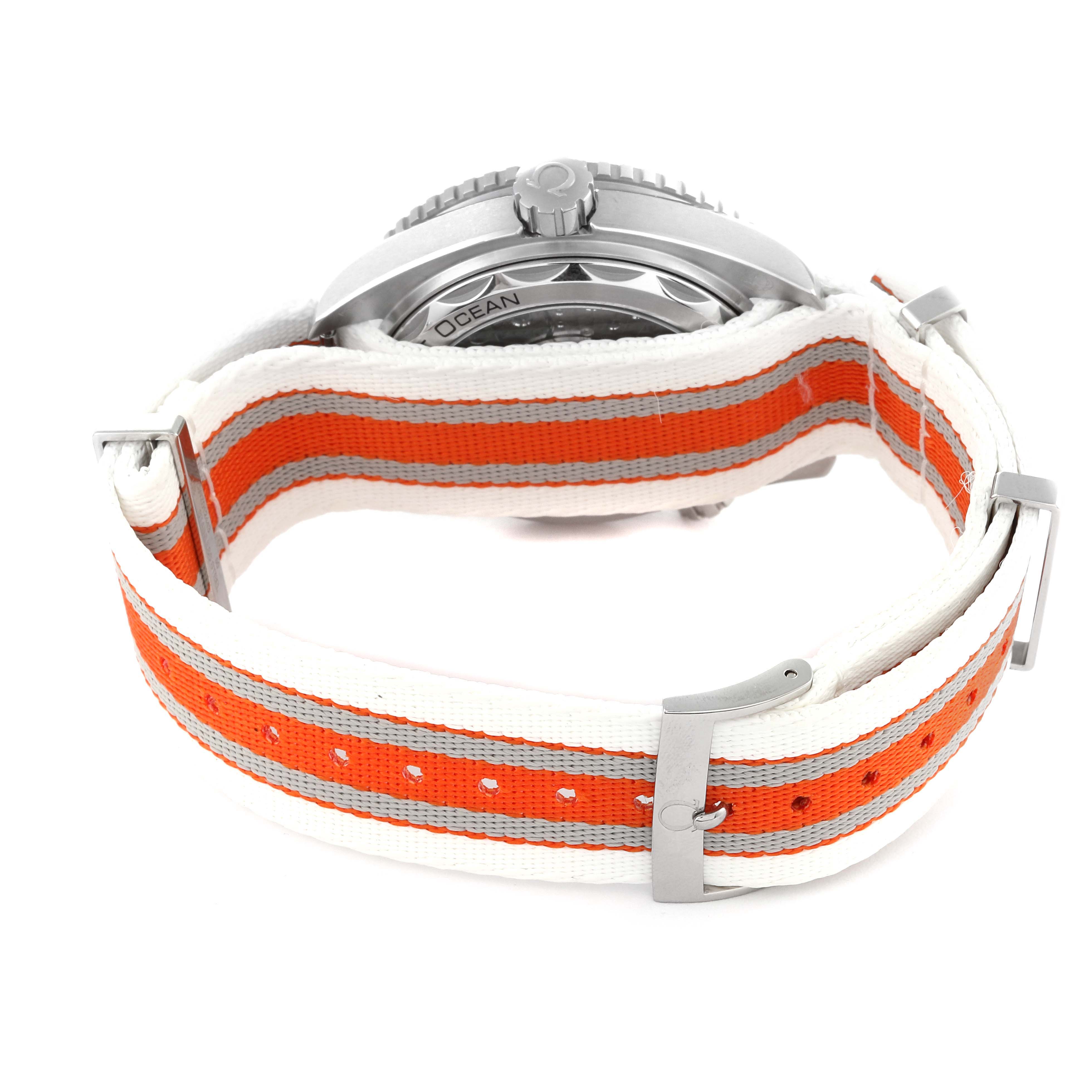 The Omega Planet Ocean 215.32.44.21.04.001 Men's Stainless Steel White Dial 215.32.44.21.04.001 Men's Stainless Steel White Dial watch is pictured from the back, displaying the case and crown, and features an orange and white fabric strap.