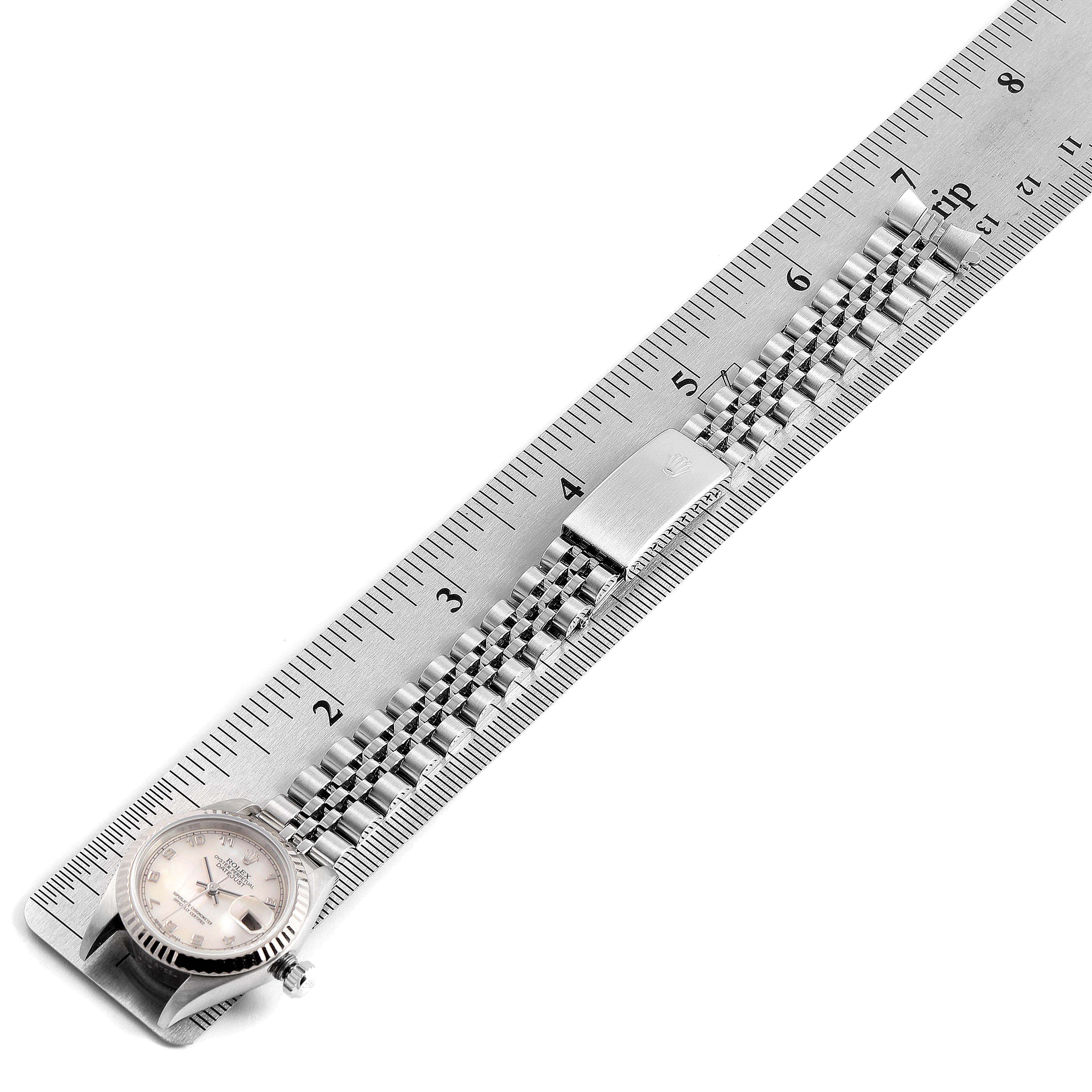 This image shows the Rolex Datejust 79174 Women's Stainless Steel Mother of Pearl Dial 79174 Women's Stainless Steel Mother of Pearl Dial watch laid flat next to a ruler, displaying its face, bezel, bracelet, and clasp.