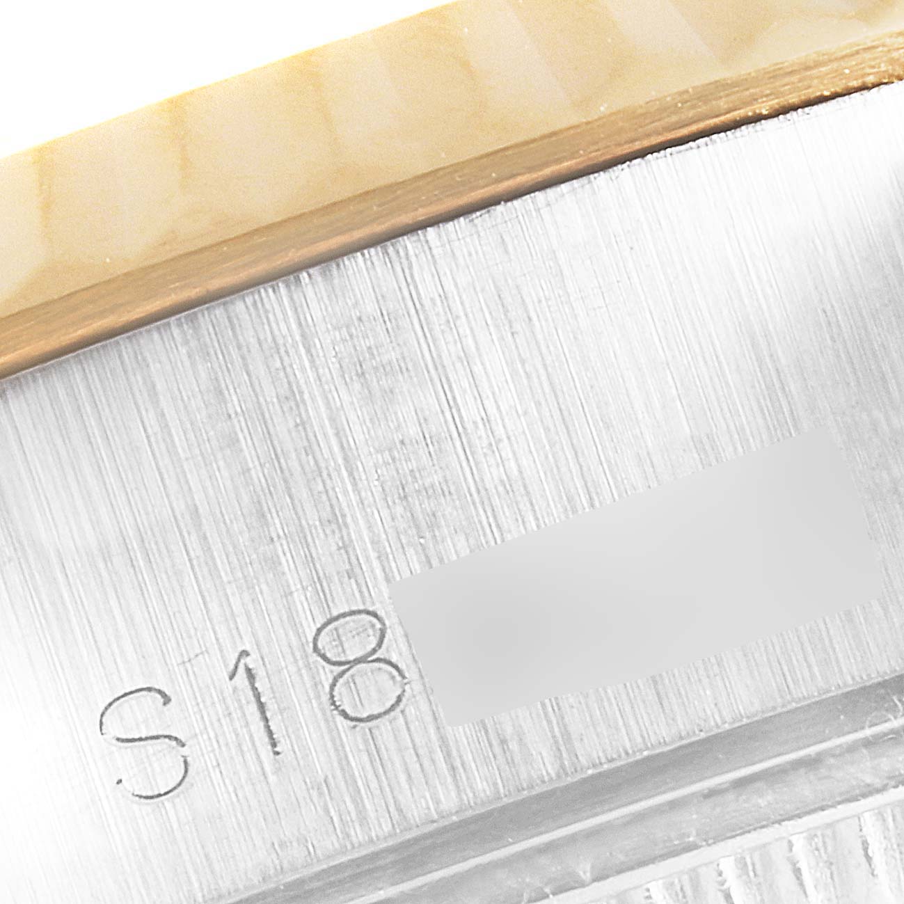 This close-up image of a Rolex Datejust 69173 Women's Stainless Steel Beige Dial 69173 Women's Stainless Steel Beige Dial watch shows parts of the bezel and the engraved serial number on the side of the case.