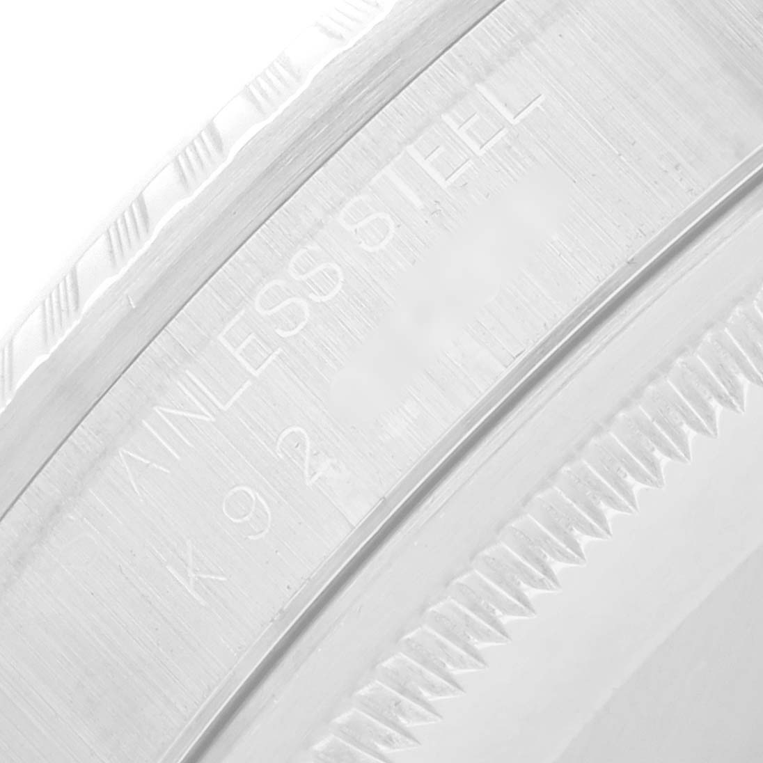 The image shows a close-up of the Rolex Datejust 16220 Men
s Stainless Steel White Dial model
s fluted bezel, highlighting the "Stainless Steel" engraving.