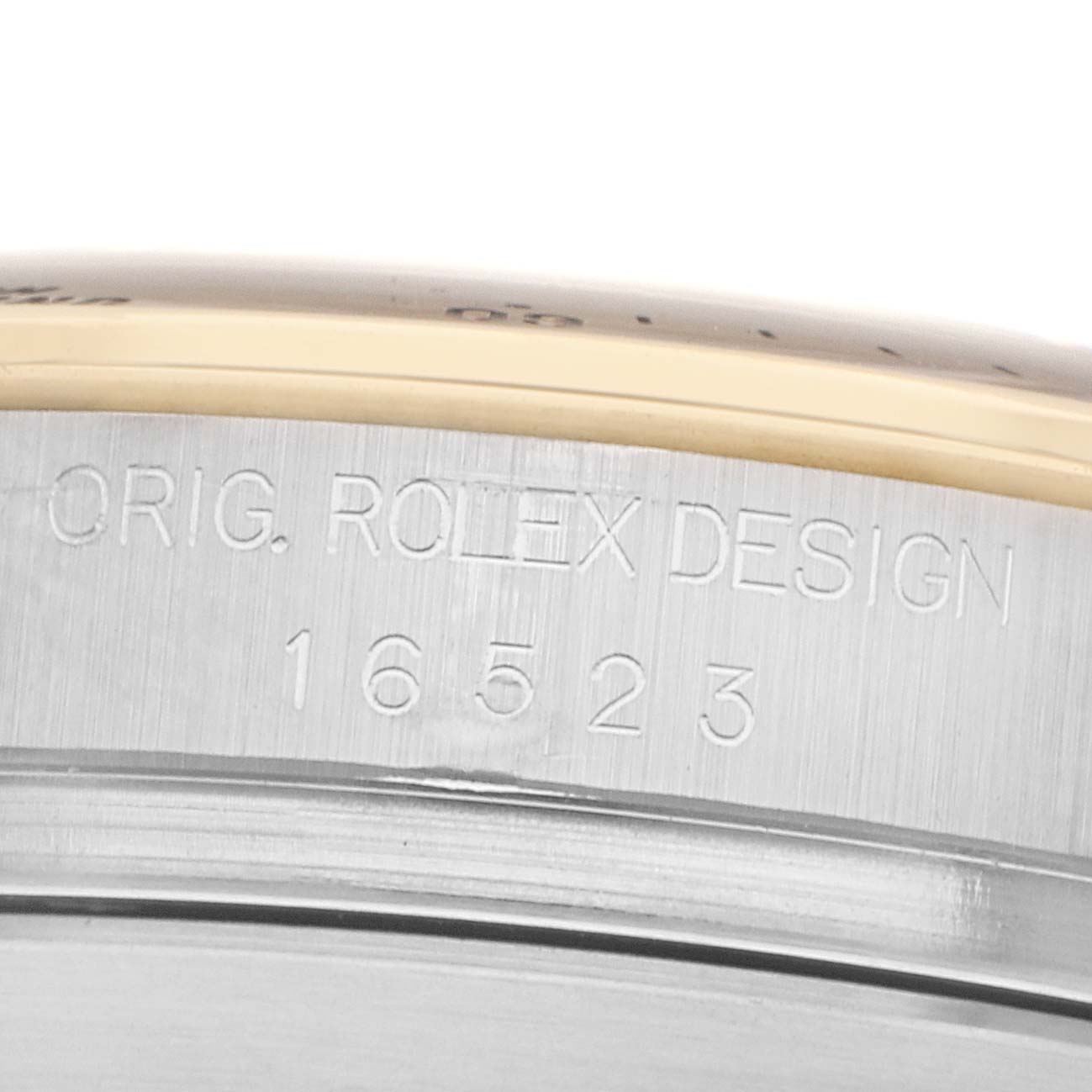 The image shows a close-up of the side of a Rolex Daytona 16523 Men
s Steel and Gold (two tone) Black Dial watch case, highlighting the engraved model number and "ORIG. ROLEX DESIGN."