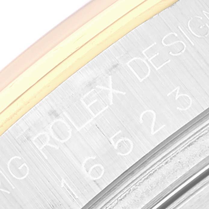 This close-up of the Rolex Daytona 16523 Men's Steel and Gold (two tone) White Dial 16523 Men's Steel and Gold (two tone) White Dial watch shows the engraved "Rolex Design" text and part of the bezel.