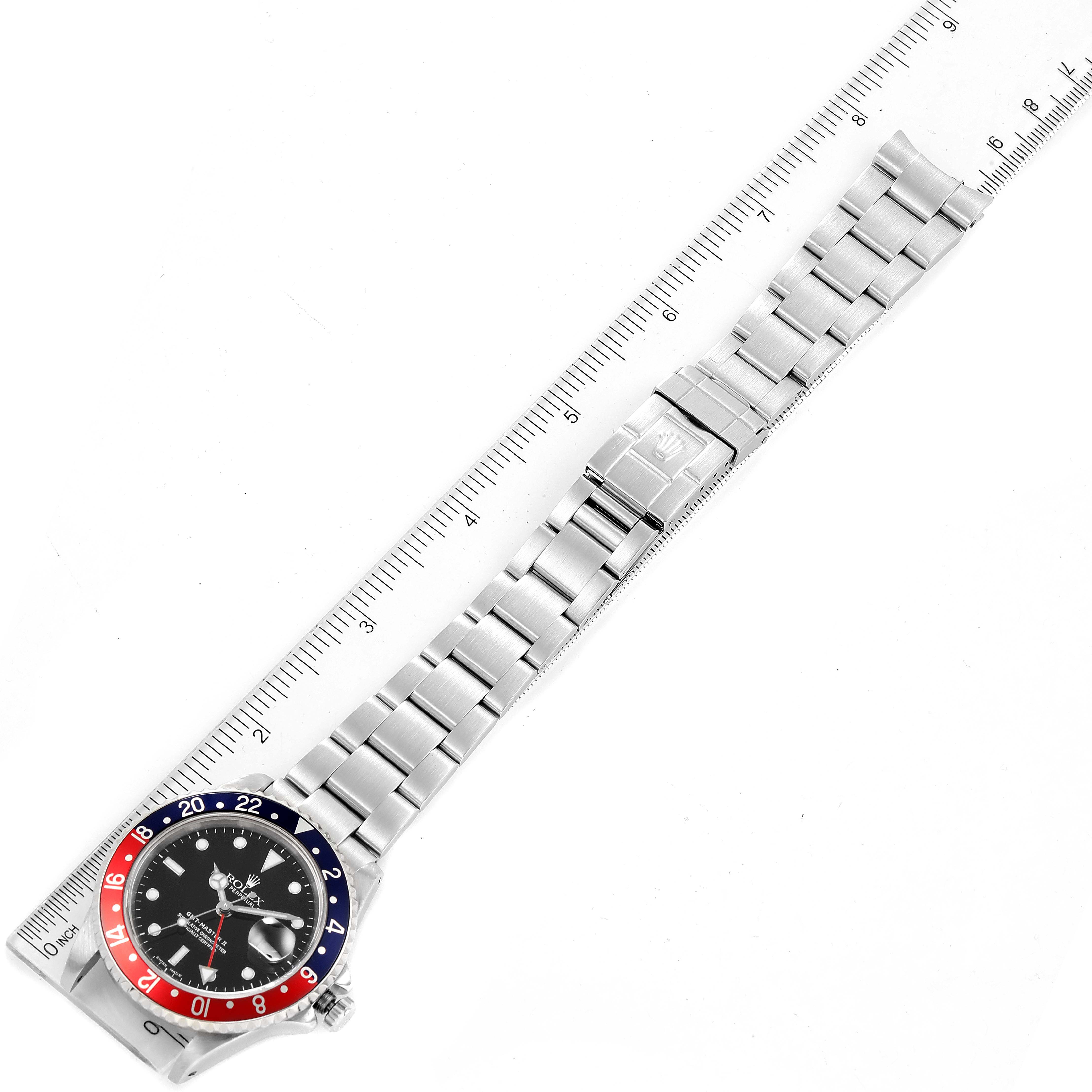 The image shows a top view of the Rolex GMT-Master 16710 Men
s Stainless Steel Black Dial 16710 Men
s Stainless Steel Black Dial watch with its full metal bracelet and a ruler for scale.