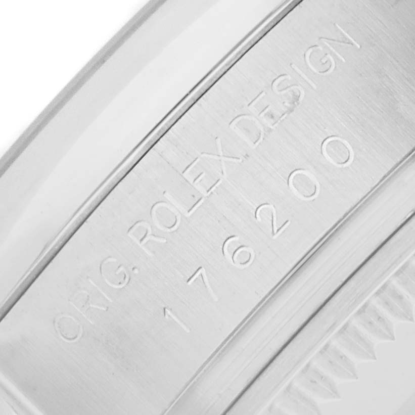 The image shows a close-up of the inner bezel of a Rolex Oyster Perpetual 176200 Women
s Stainless Steel Pink Dial, featuring engraved design text.