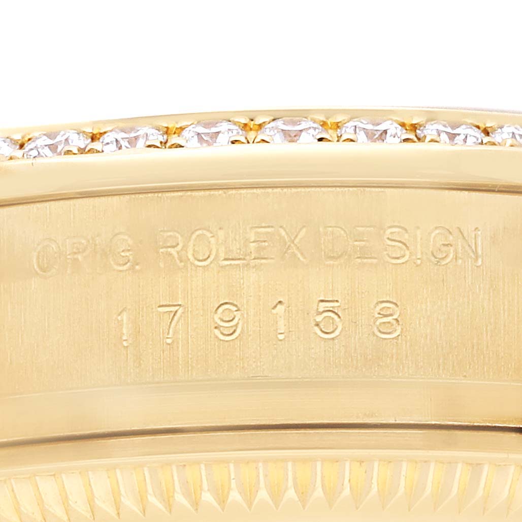 The image shows a close-up of the side of the Rolex Datejust 179158 Women
s Yellow Gold Champagne Dial watch, highlighting its engraved serial number and diamond-set bezel.