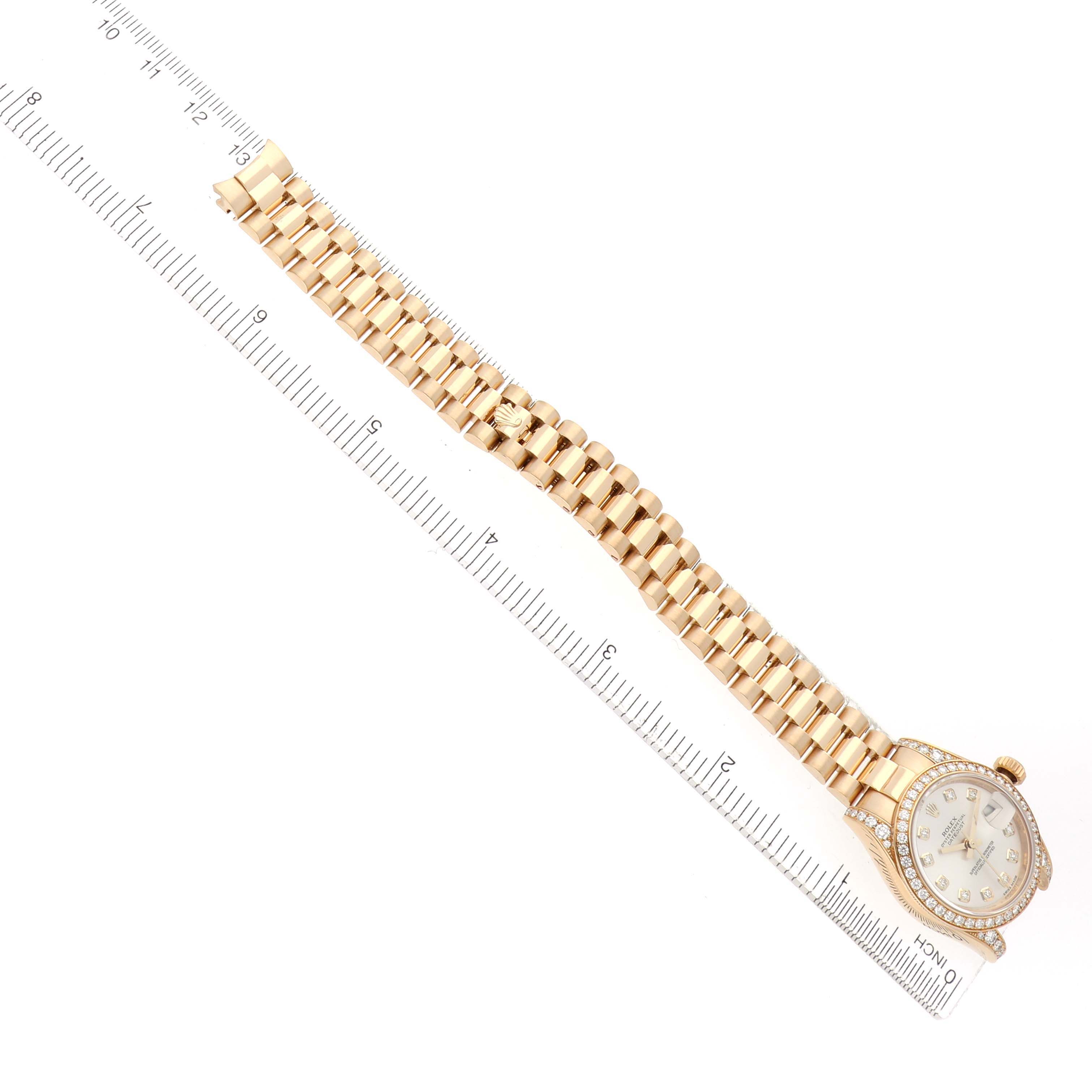 The Rolex President 179158 Women
s Yellow Gold Silver Dial watch is shown from an overhead angle, highlighting its bracelet, dial, and bezel with a ruler alongside.