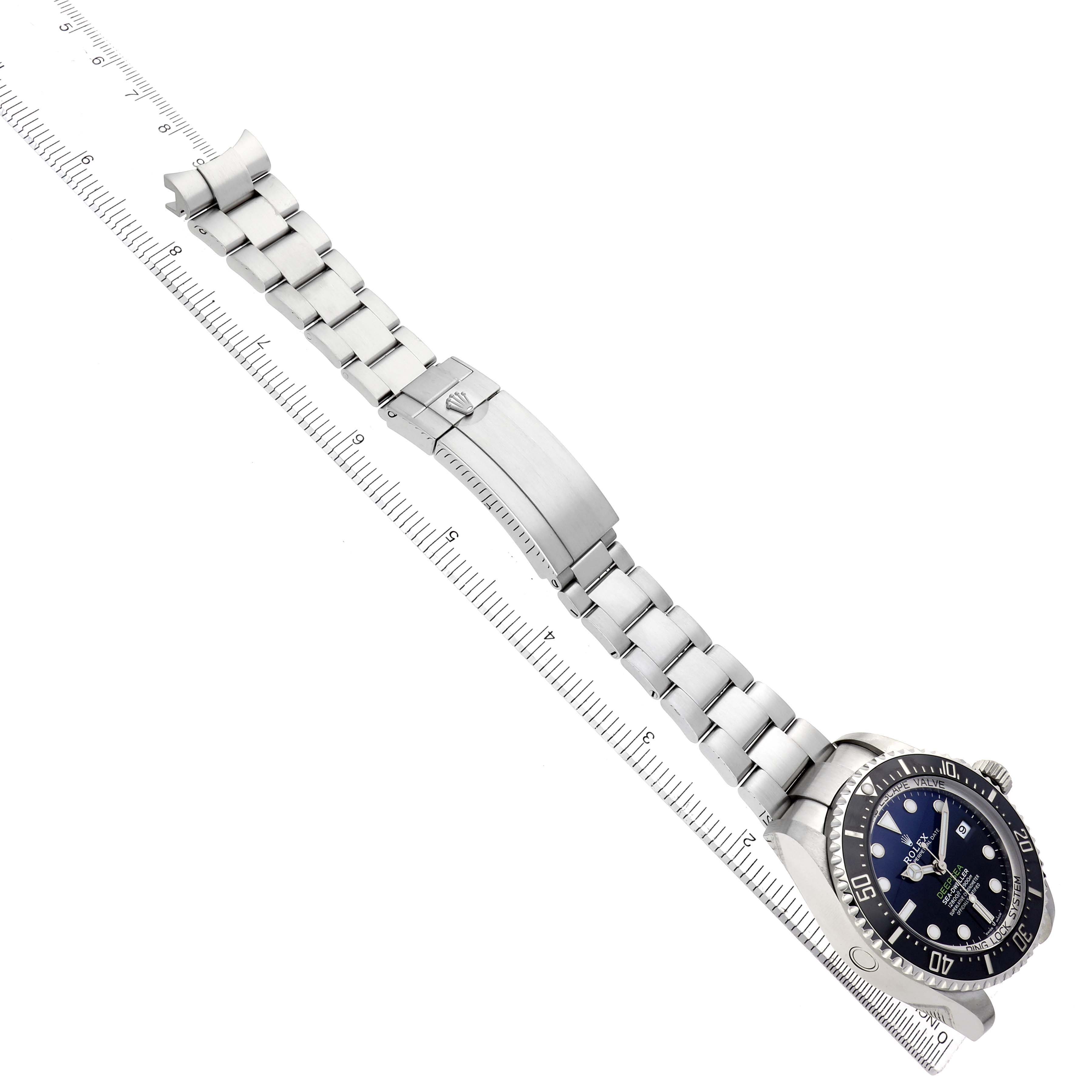 The Rolex Sea-Dweller 136660 Men
s Stainless Steel Blue Dial watch is shown from a top view, displaying the bracelet, clasp, and face alongside a ruler for scale.