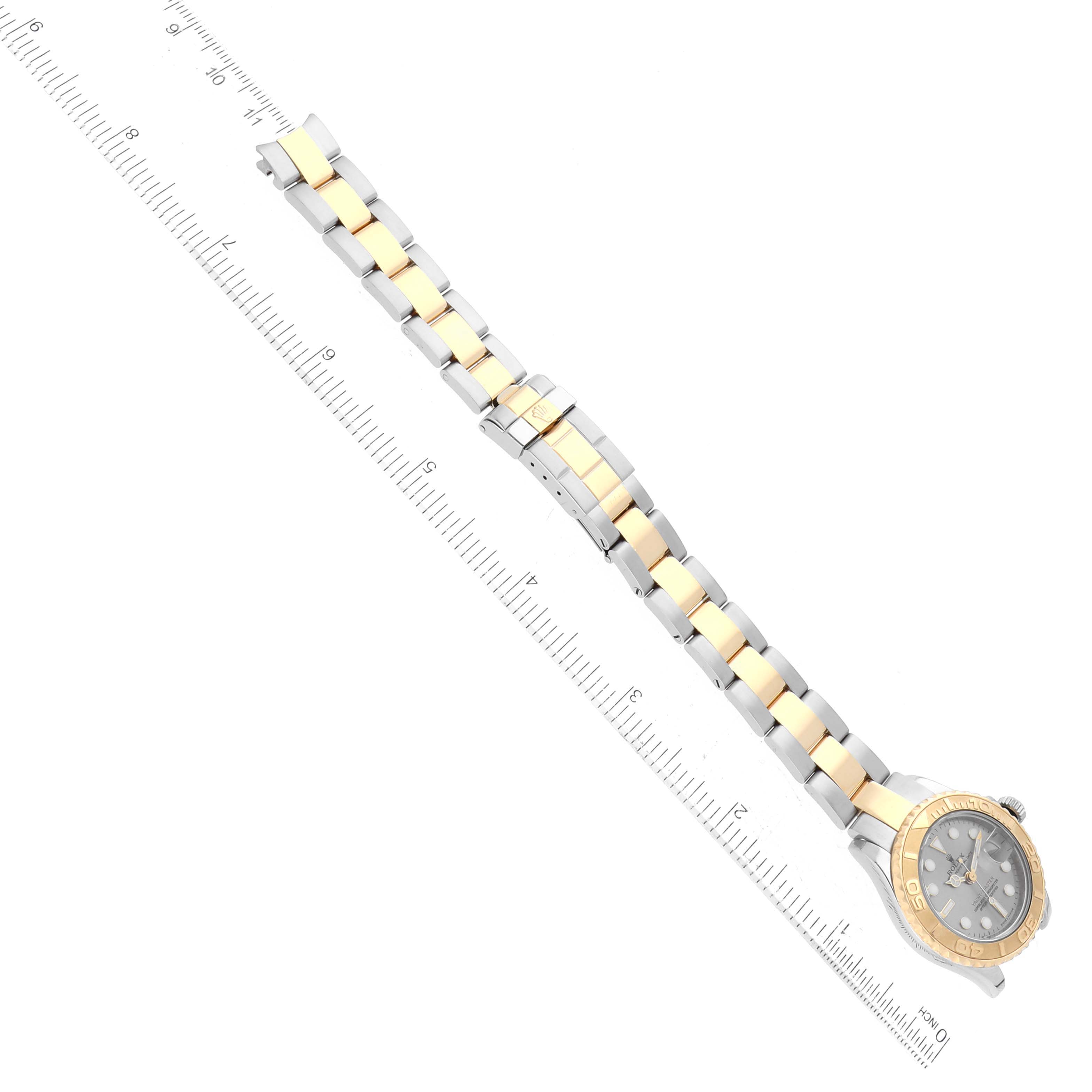 The image shows a top-down view of a Rolex Yacht-Master 169623 Women's Steel and Gold (two tone) Grey Dial 169623 Women's Steel and Gold (two tone) Grey Dial watch with a two-tone metal bracelet alongside a measuring ruler.