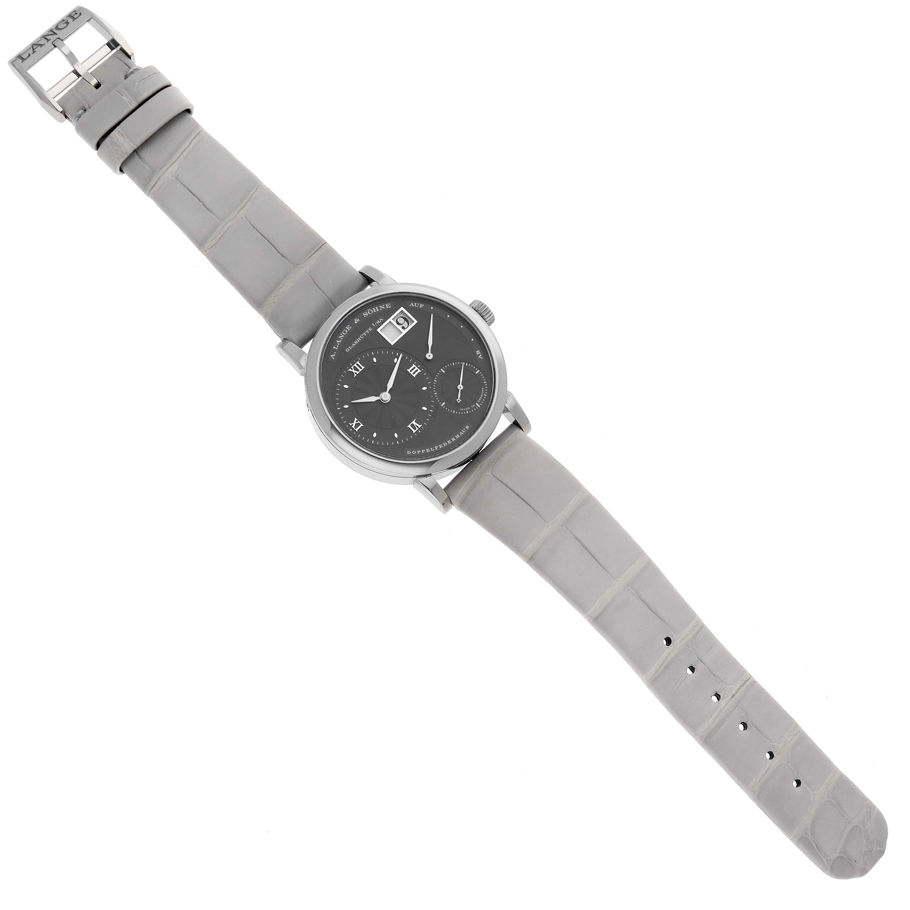 The image shows a Lange 1 watch by A. Lange & Söhne from a top-down angle, featuring its face, strap, and buckle.