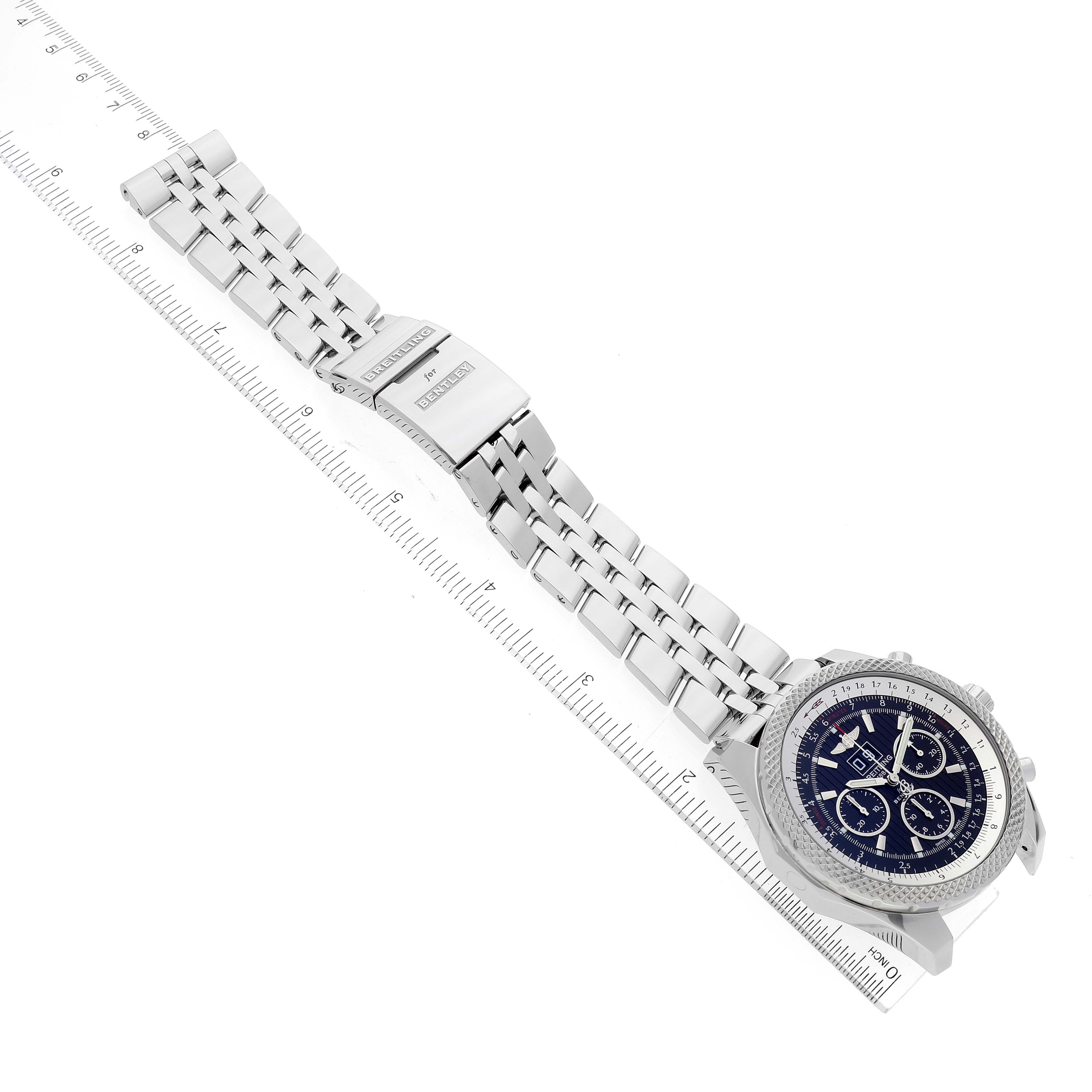 The image shows the Breitling Bentley A44364 Men's Stainless Steel Black Dial A44364 Men's Stainless Steel Black Dial watch laid flat at an angle alongside a ruler, highlighting its stainless steel bracelet and clasp.