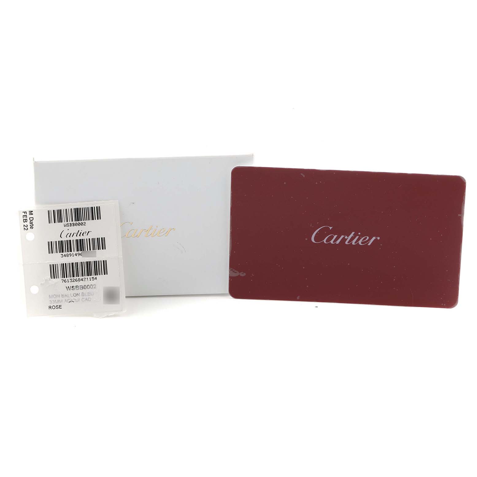 The image shows the packaging and cards for a Cartier Ballon Bleu WSBB0002 Women
s Stainless Steel Pink Dial watch, including a white box, a red card, and a tag.