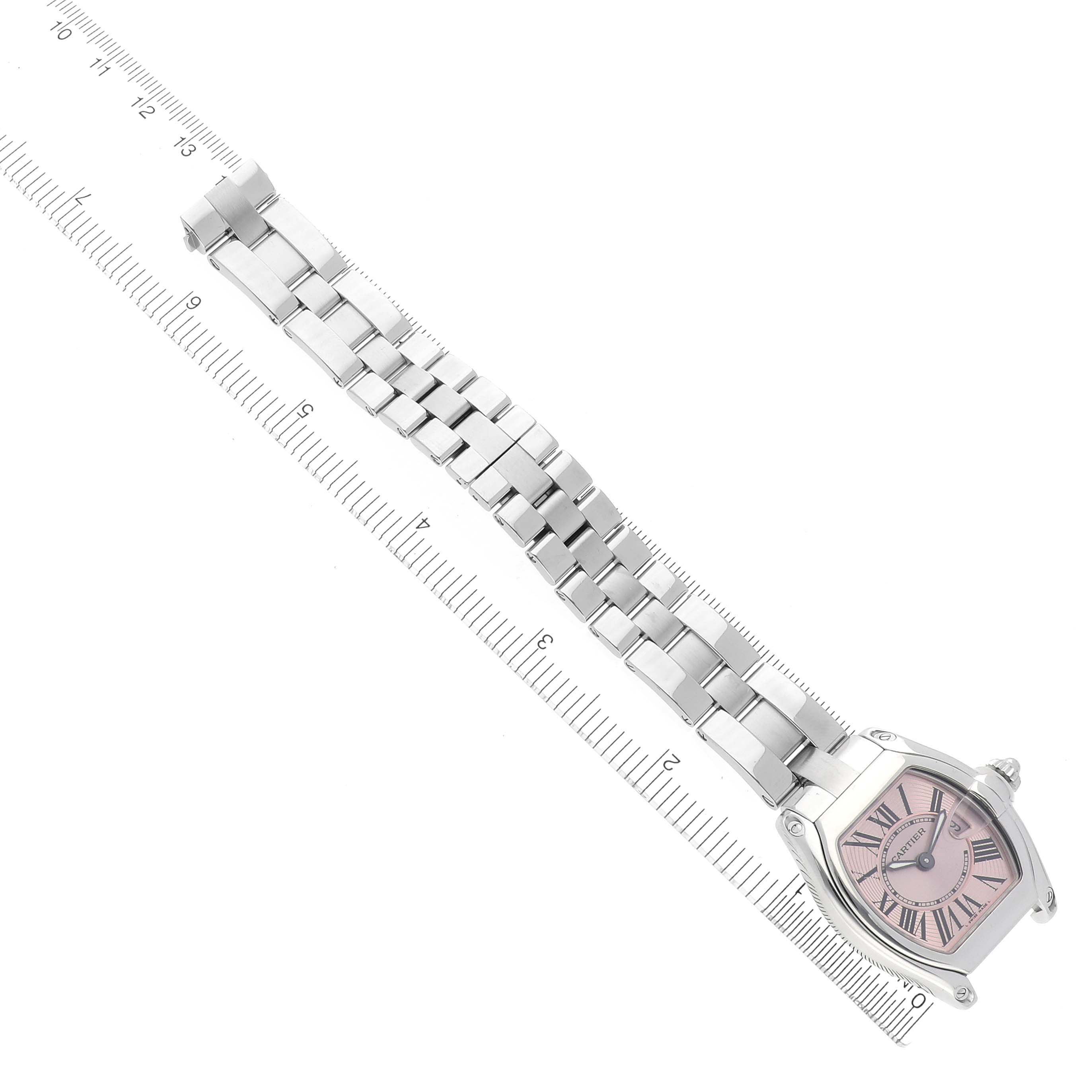 This image shows a Cartier Roadster W62017V3 Women's Stainless Steel Pink Dial W62017V3 Women's Stainless Steel Pink Dial watch at an oblique angle, highlighting its face and linked bracelet, with a measuring ruler beneath.