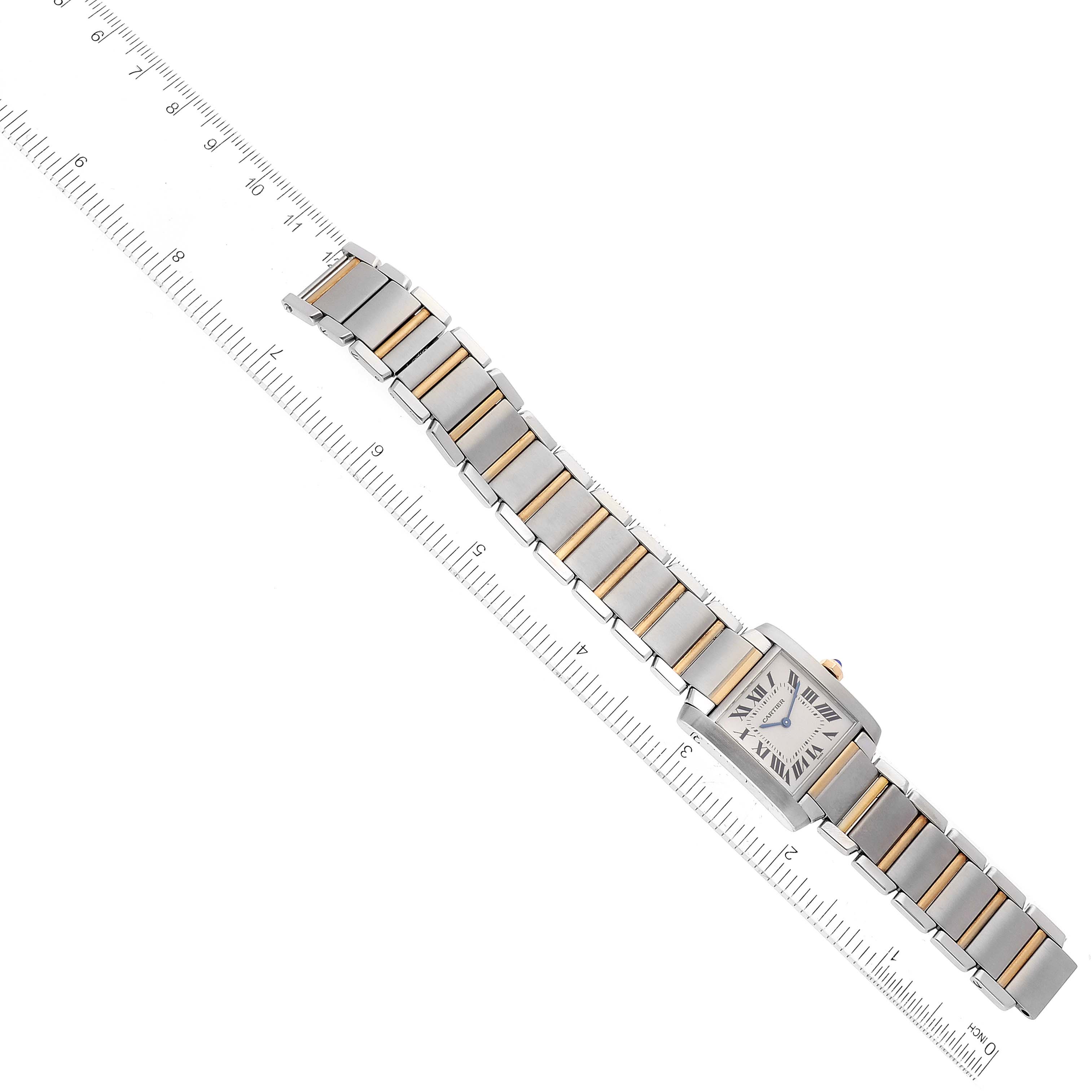 The image shows an overhead view of a Cartier Tank Française watch, highlighting its face and metal bracelet with a ruler for scale.