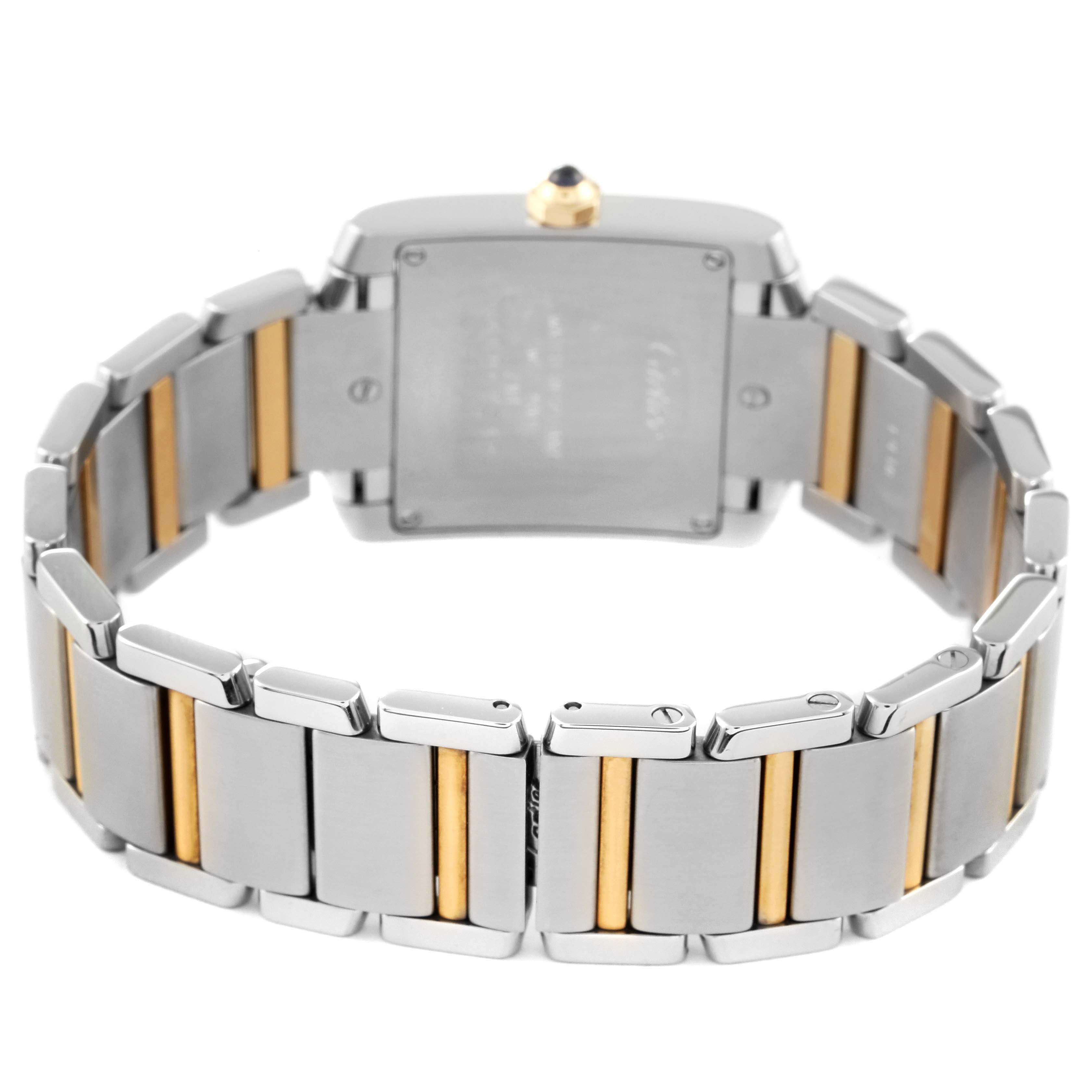 The Cartier Tank Française watch is shown from the back, highlighting the stainless steel and gold bracelet.