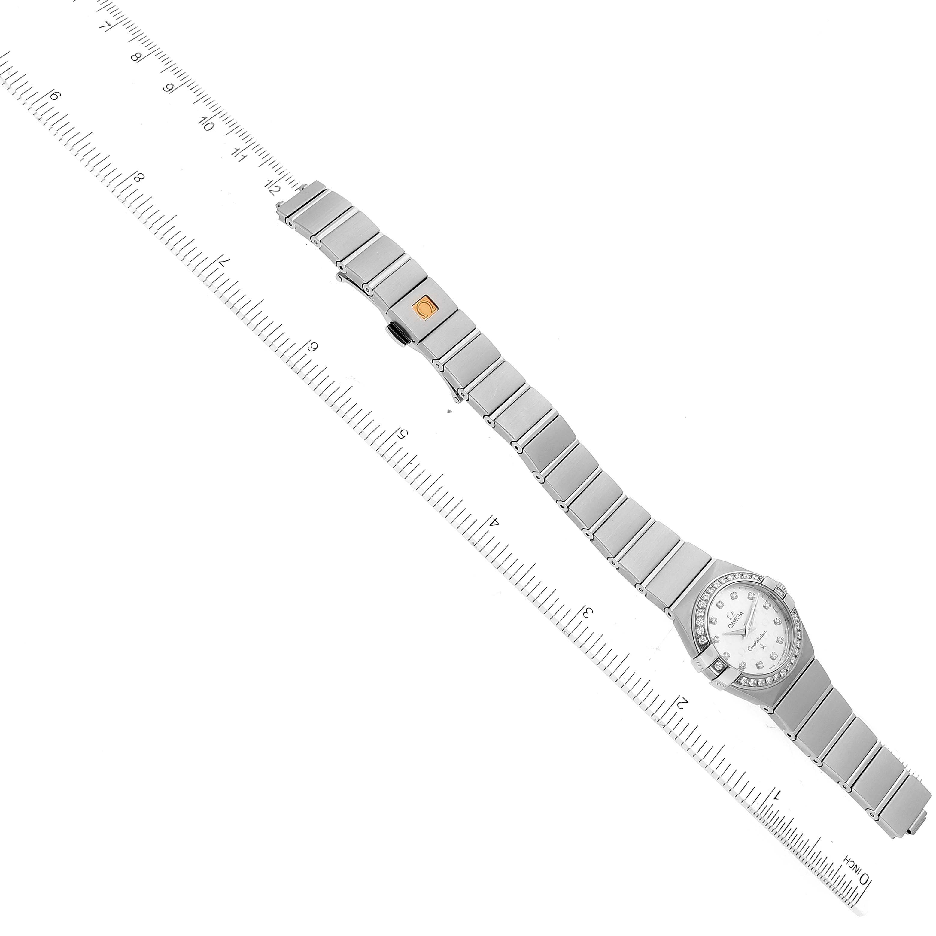 The image shows an overhead view of the Omega 123.15.24.60.52.001 Women's Stainless Steel Silver Dial 123.15.24.60.52.001 Women's Stainless Steel Silver Dial Constellation Diamond Steel Ladies Watch 123.15.24.60.52.001 laid flat, with a ruler for scale.
