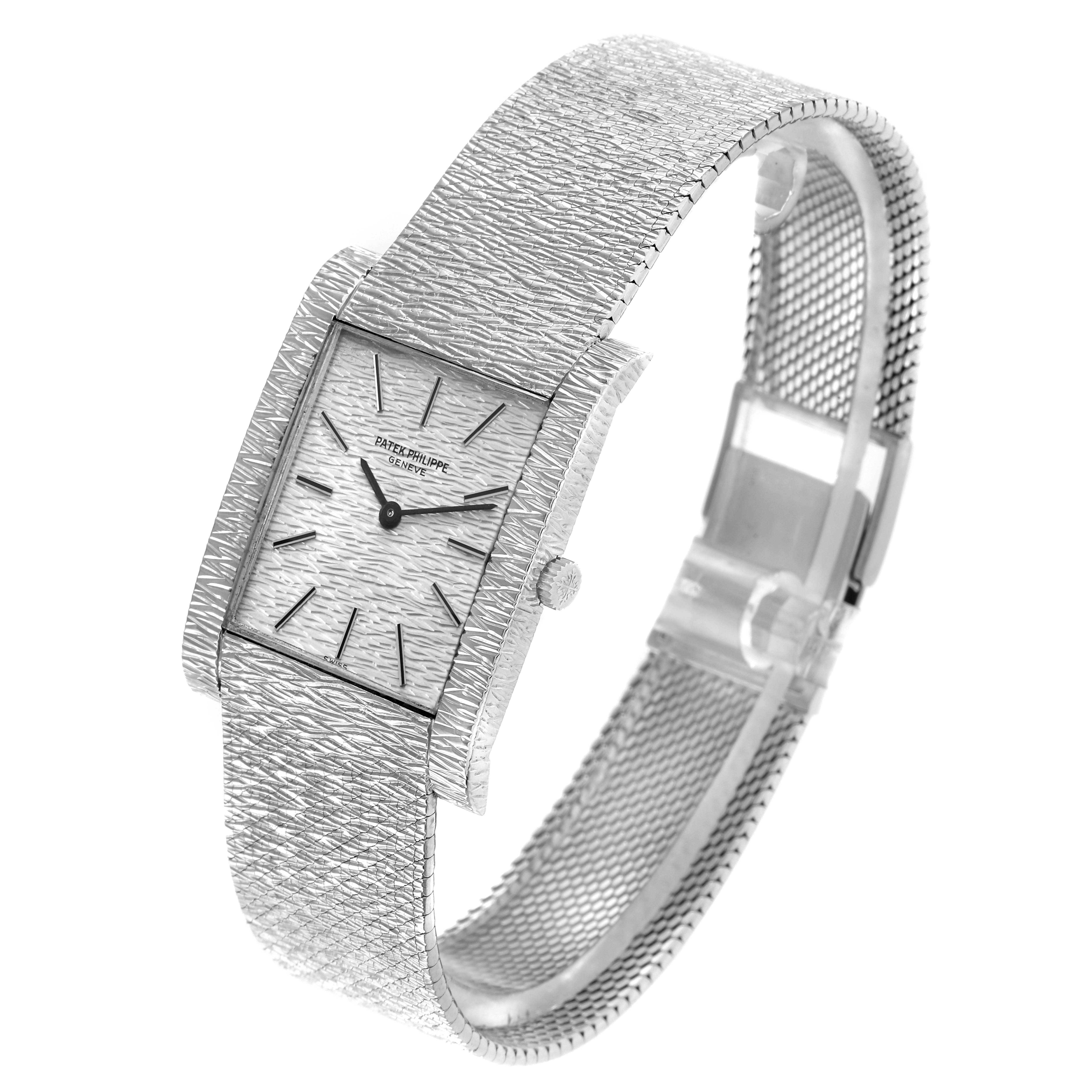 The Vintage Patek Philippe watch is shown at an angled view, highlighting its textured dial, rectangular case, and mesh bracelet.