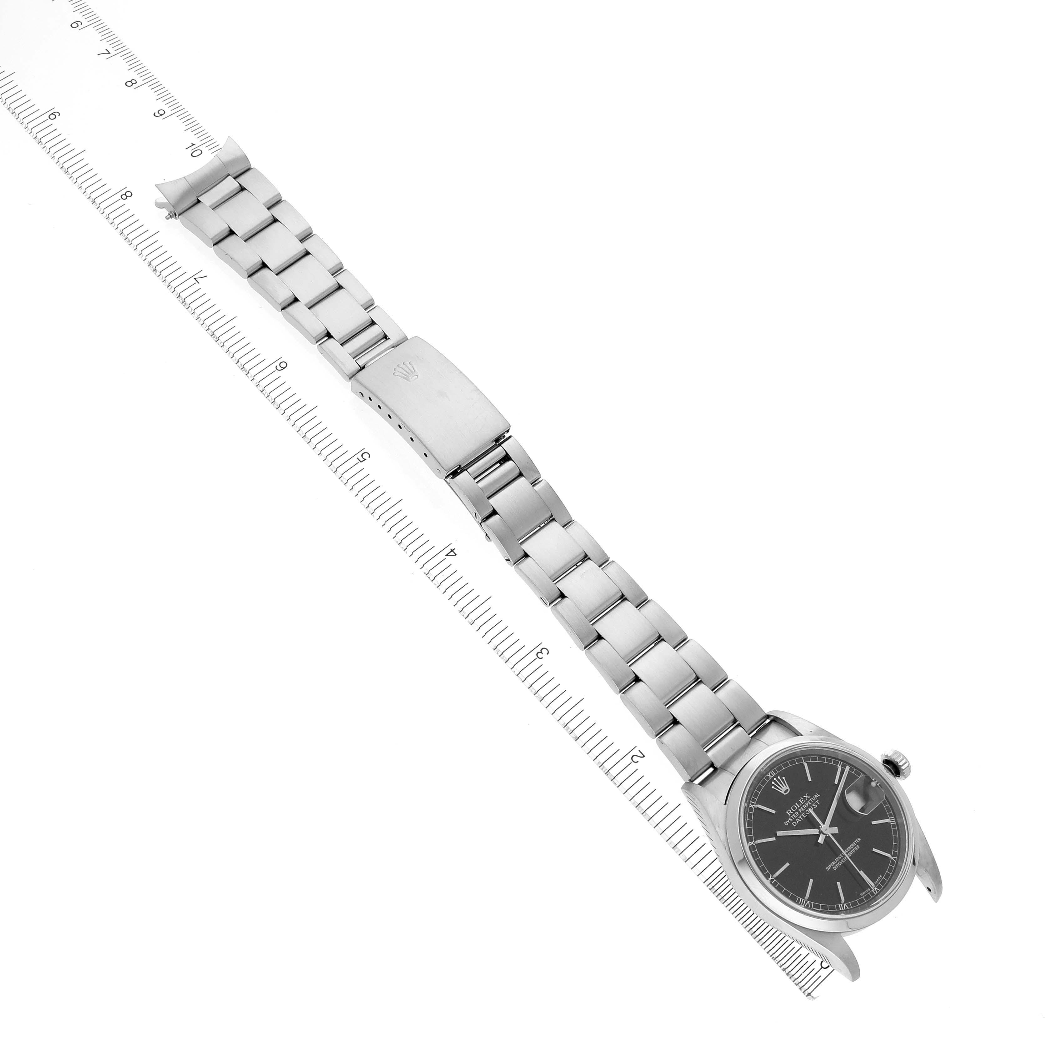 The image shows a top-down view of a Rolex Datejust 16200 Men
s Stainless Steel Black Dial 16200 Men
s Stainless Steel Black Dial watch, displaying its bracelet, clasp, and watch face with a ruler for scale.